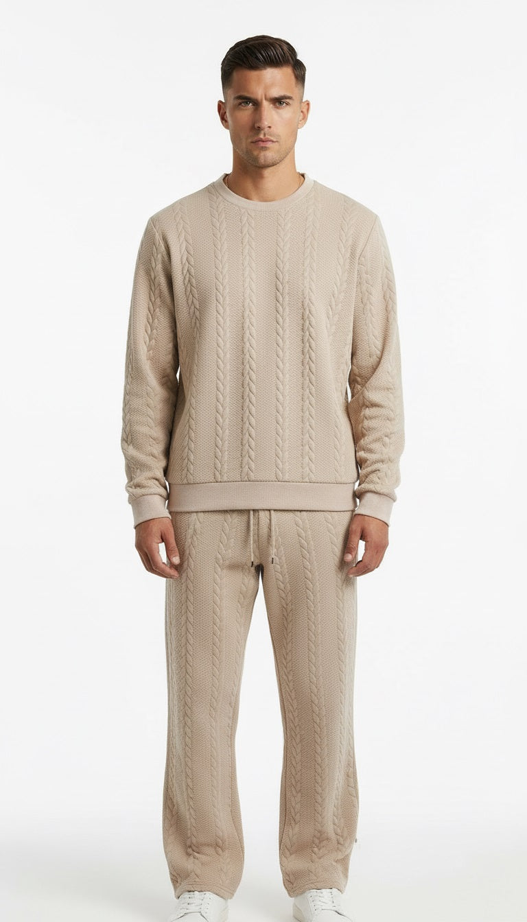 Man wearing a beige cable knit sweater and pants on a white background