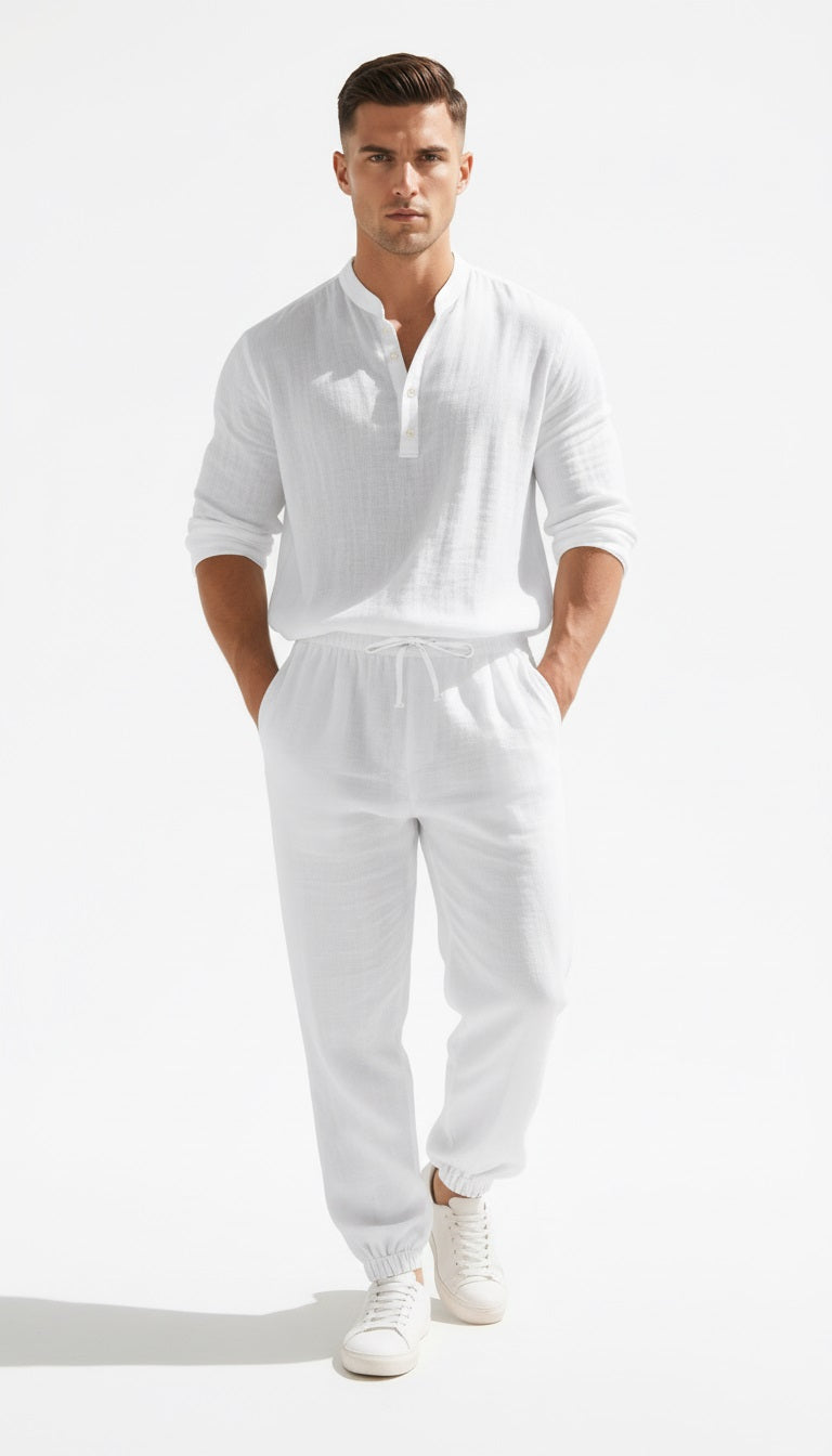 Man in a white outfit standing on a balcony with a view of the ocean and yachts.