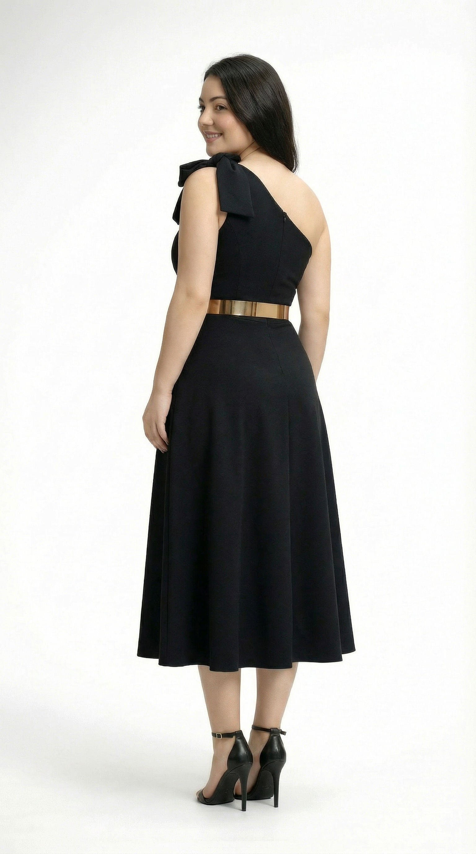 Woman wearing a black one-shoulder dress with a gold belt on a white background
