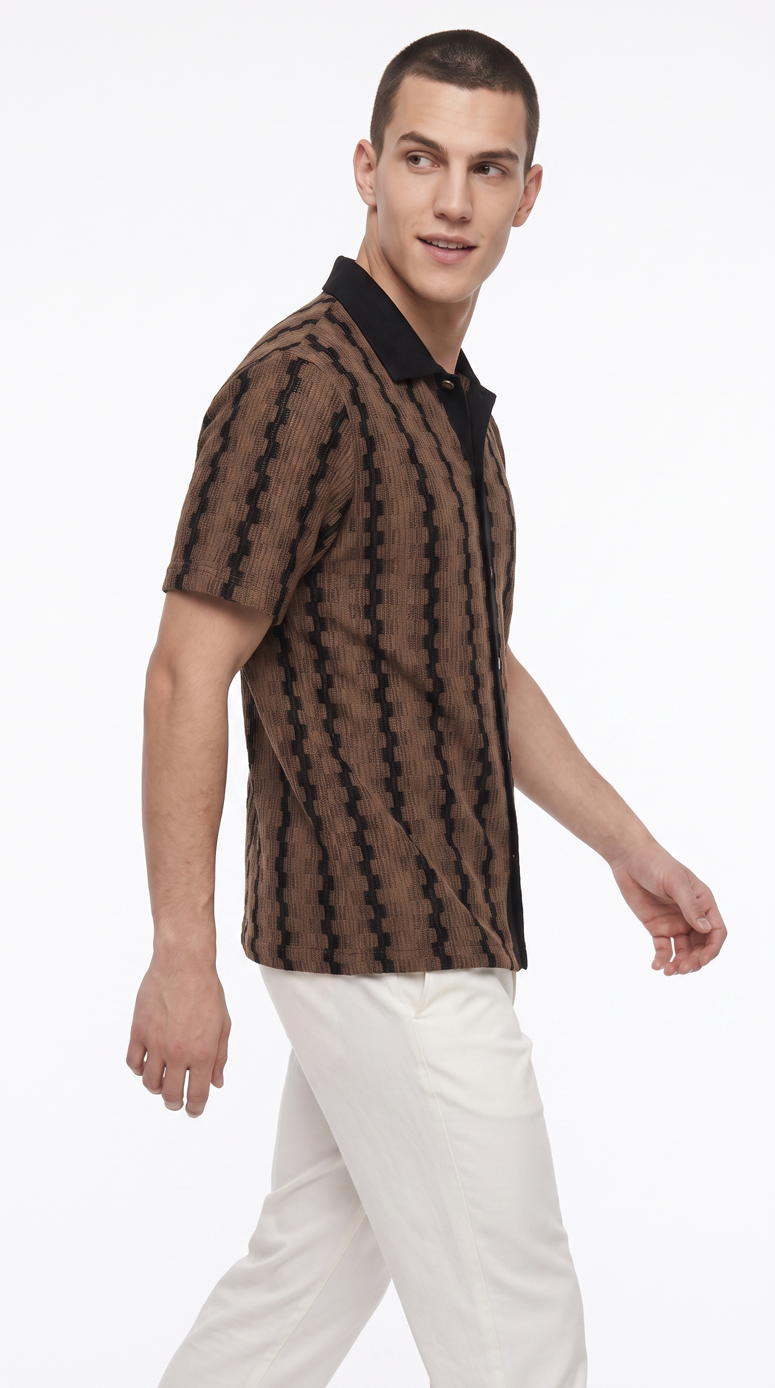 A man wearing a brown and black patterned short-sleeve knit polo shirt with white trousers, photographed against a clean white studio background, from Meleche Fashion USA or Meléche (short as (Mé))