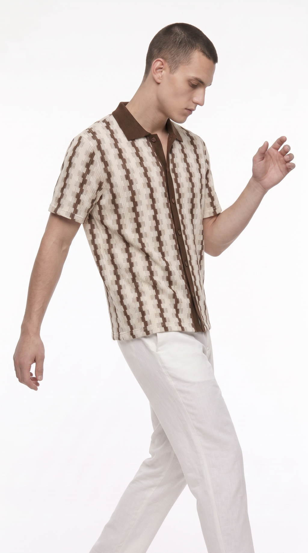 A man wearing a brown and cream patterned short-sleeve button-up shirt with white trousers, photographed against a plain white studio background, from Meleche Fashion USA or Meléche (short as (Mé))