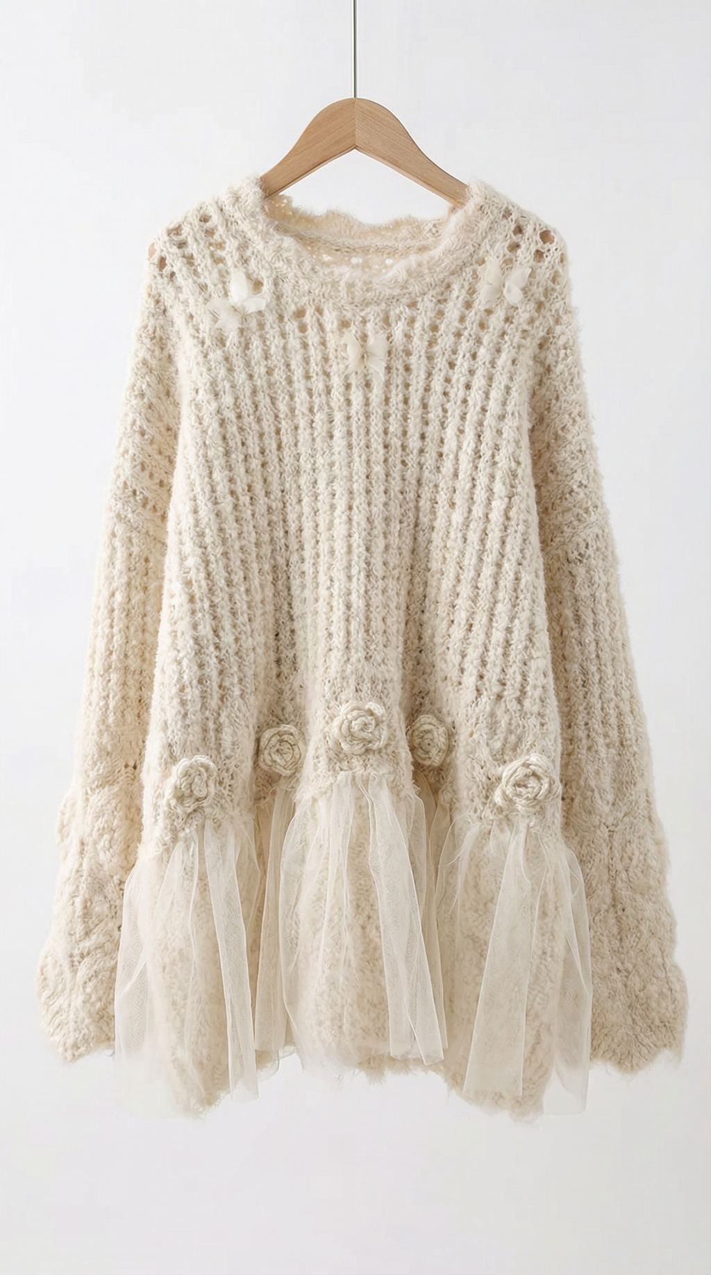 Beige knitted sweater with tassels on a wooden hanger against a white background