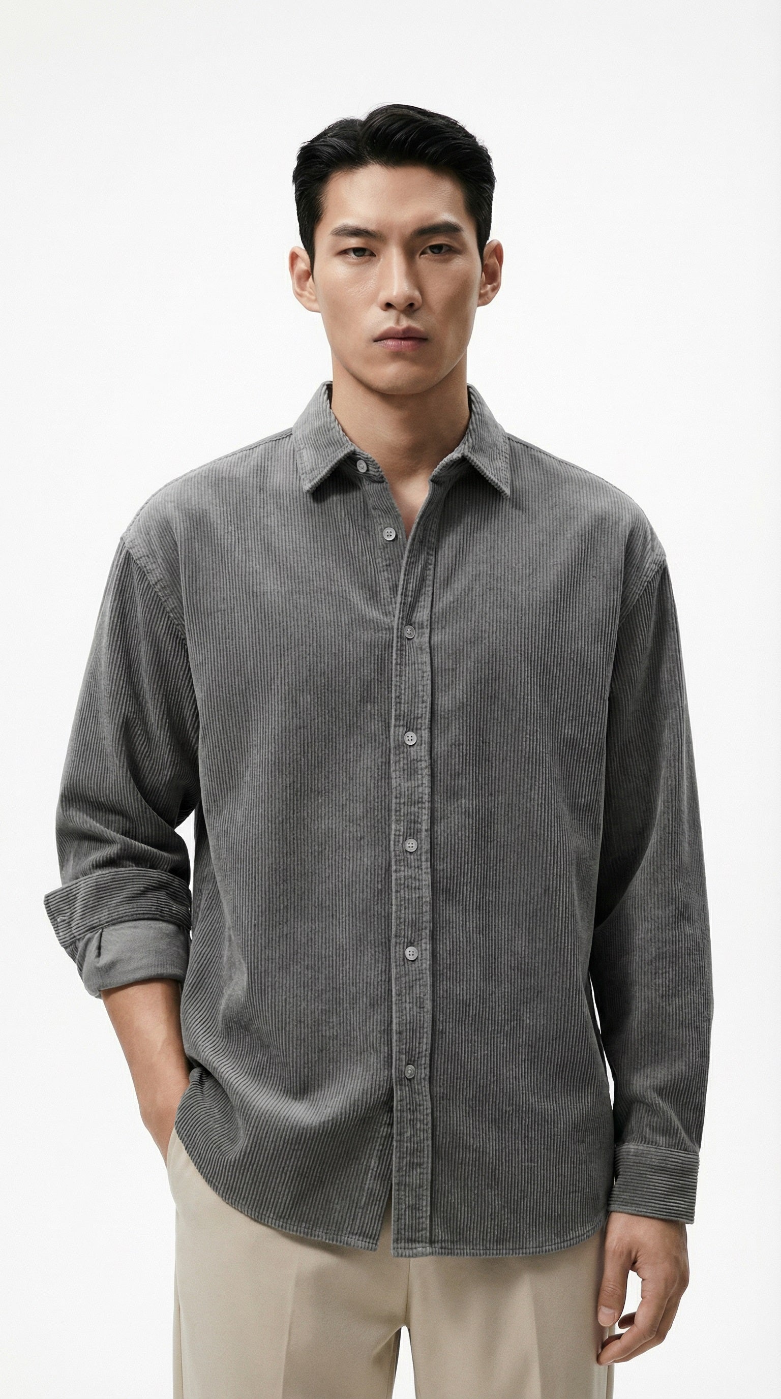 Person wearing a gray corduroy shirt holding a coffee cup on a white background