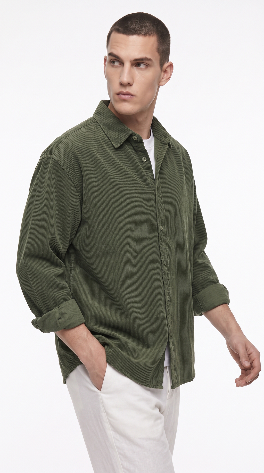 A man wearing an olive green corduroy button-down shirt over a white t-shirt and white trousers, photographed against a plain white studio background, from Meleche Fashion USA or Meléche (short as (Mé))