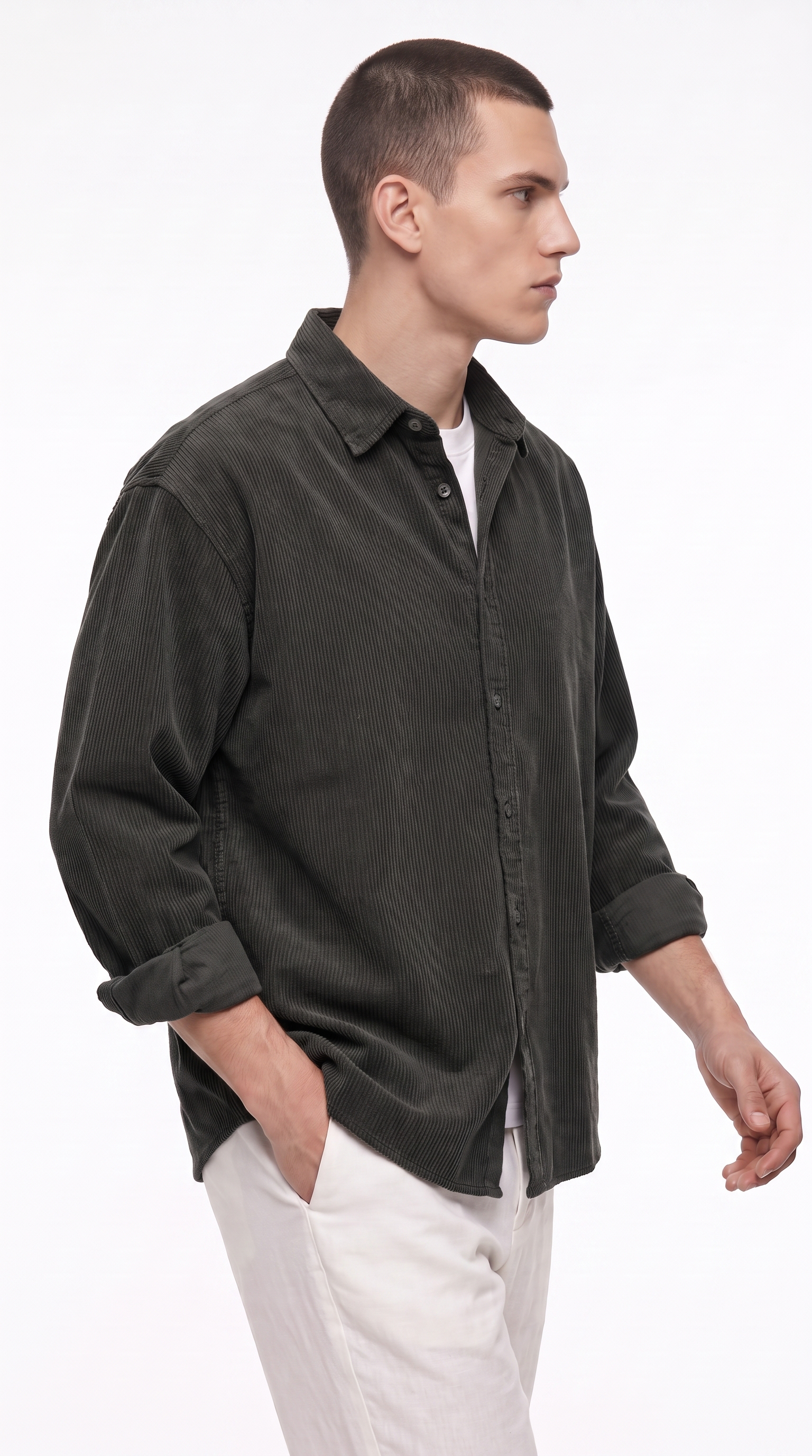 A man wearing a dark olive green corduroy button-down shirt over a white undershirt and white trousers, shown in profile against a plain white studio background, from Meleche Fashion USA or Meléche (short as (Mé))