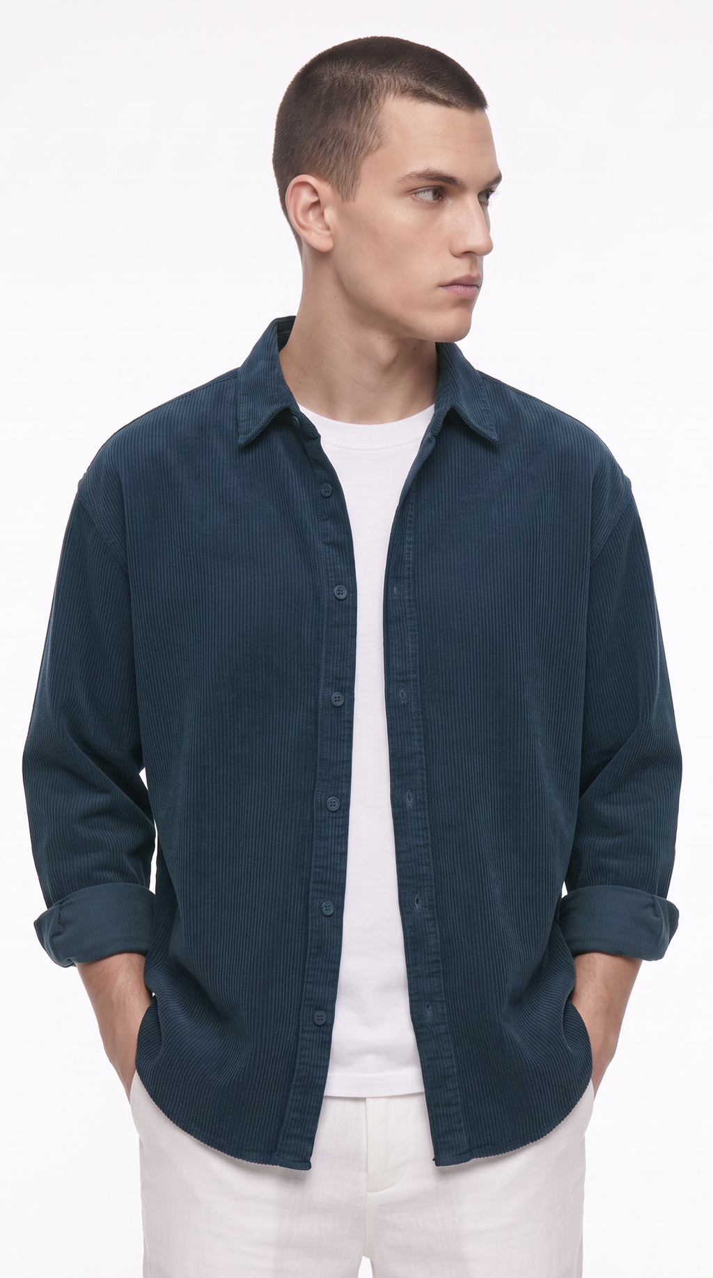 A man wearing a dark teal blue button-down shirt over a white t-shirt and white pants, standing against a plain white studio background, from Meleche Fashion USA or Meléche (short as (Mé))