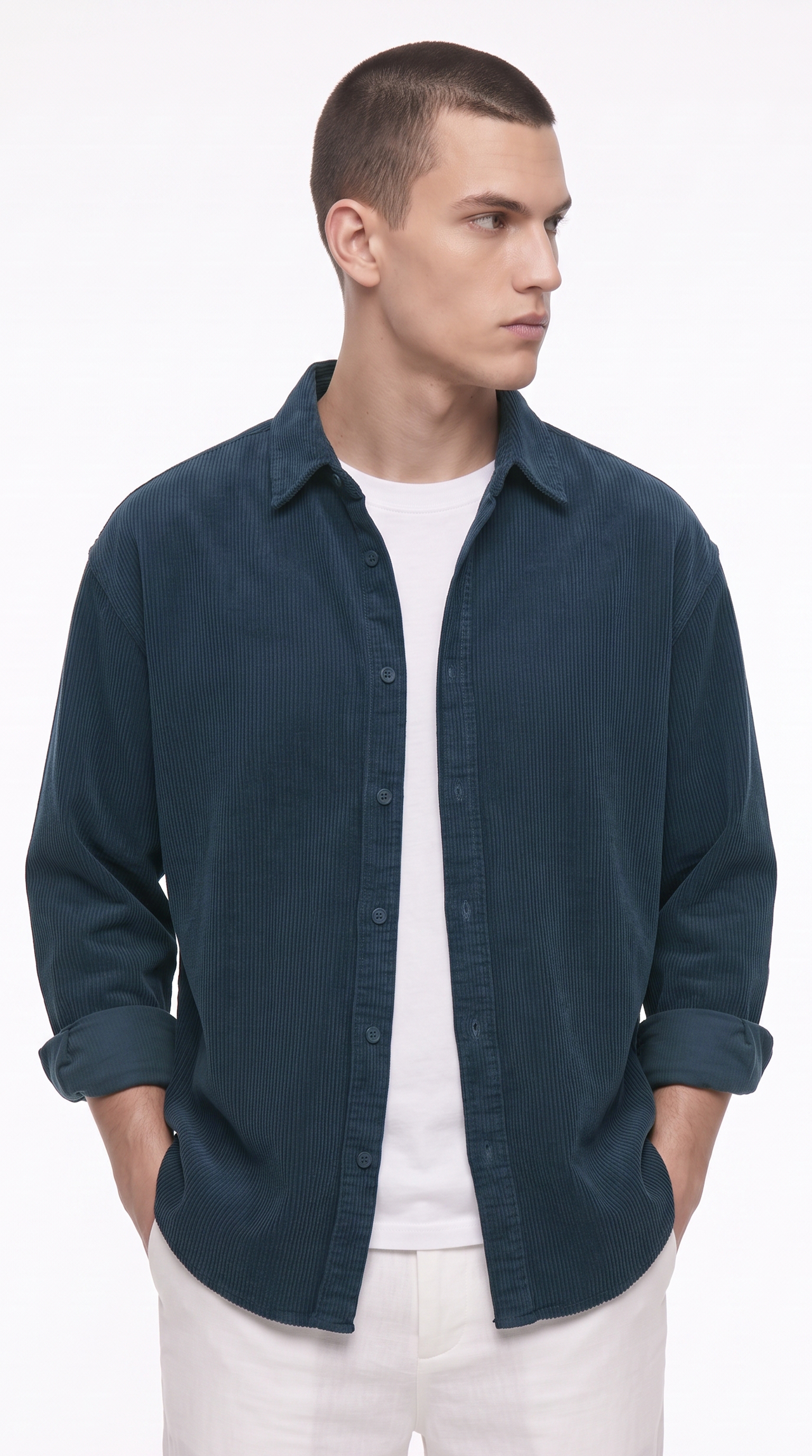 A man wearing a dark teal blue button-down shirt over a white t-shirt and white pants, standing against a plain white studio background, from Meleche Fashion USA or Meléche (short as (Mé))