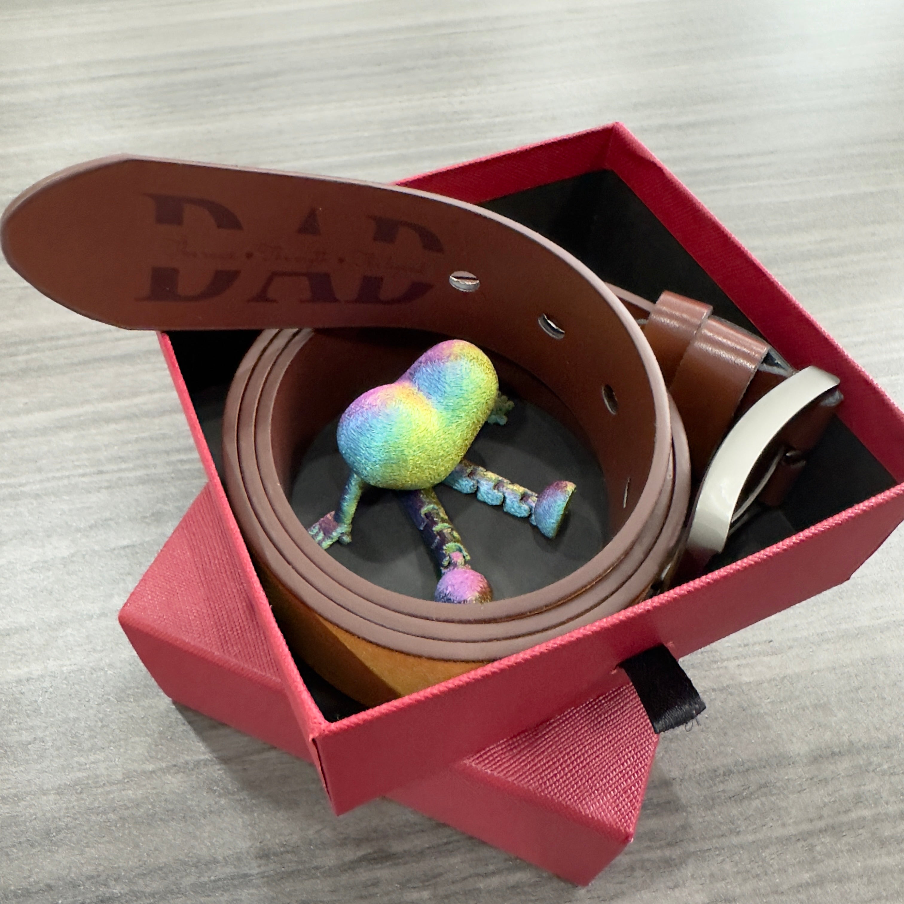 Gael belt Brown leather belt with colorful skull design in a red box on a gray surface from Meleche or Meléche (short as (Mé))