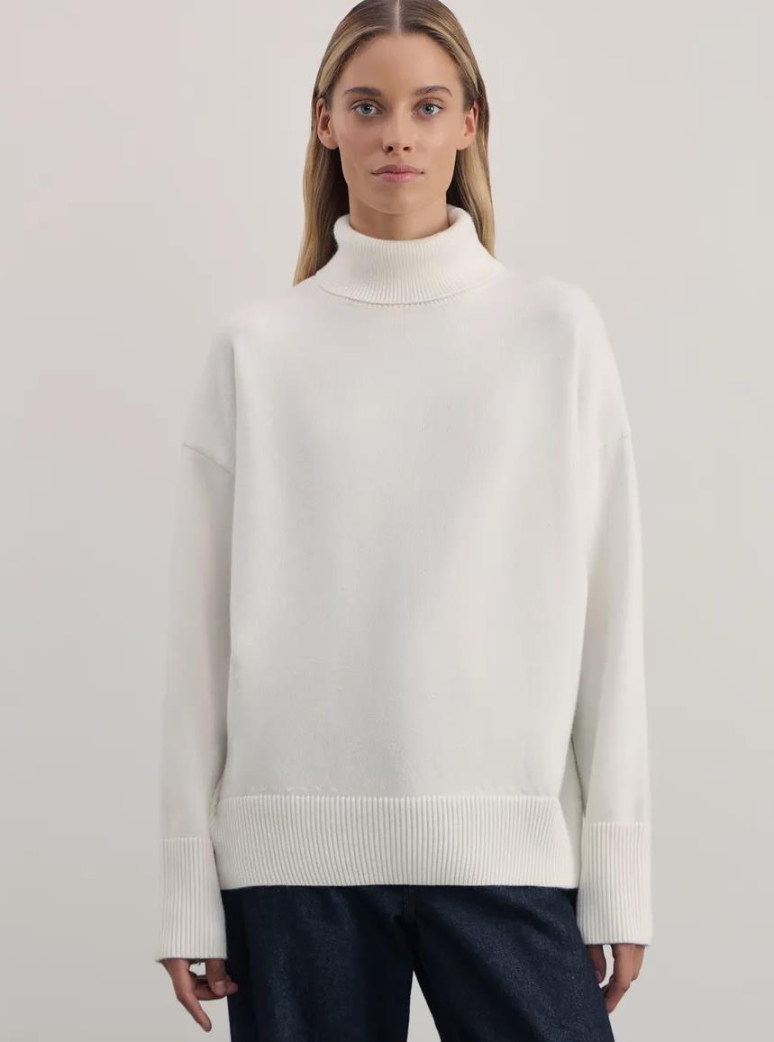 Woman wearing a white turtleneck sweater from Meleche or Meléche (short as (Mé))