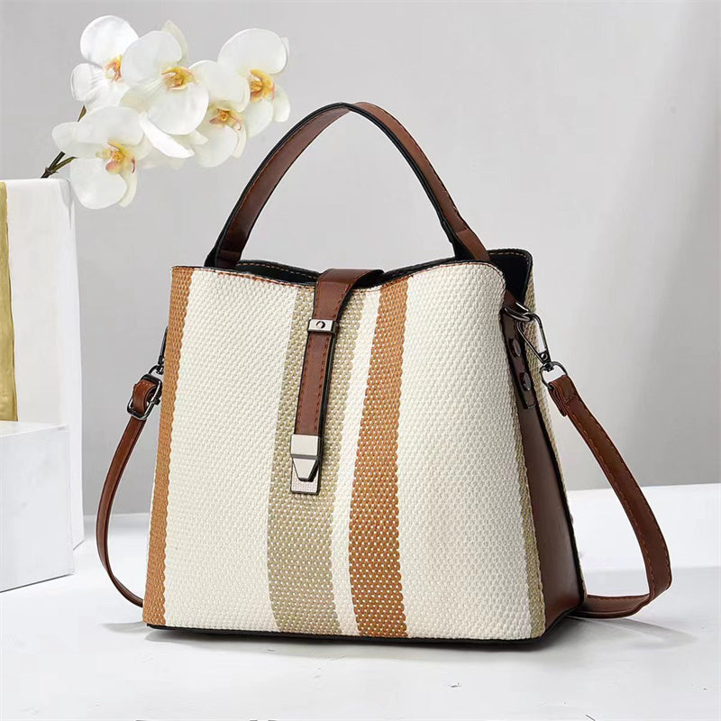 Goran Handbag with brown and beige stripes on a white surface with a white orchid in the background