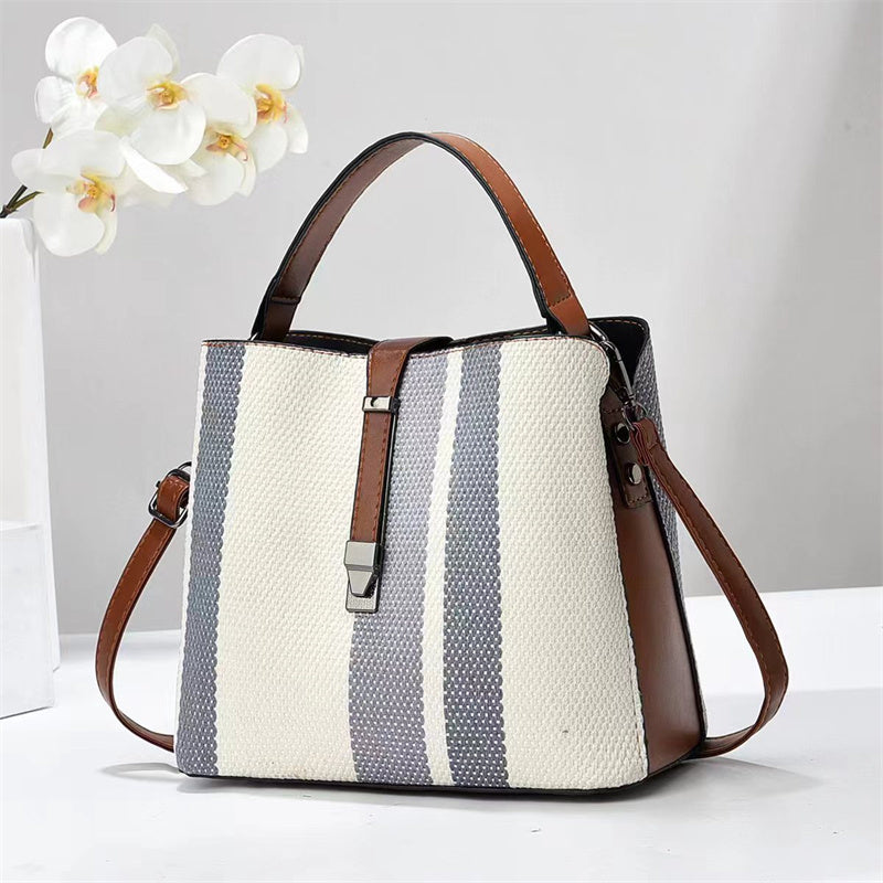 Goran Striped handbag with brown handles and trim on a white surface with a light gray background
