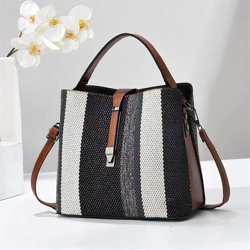 Goran Black and white striped handbag with brown accents on a light gray background