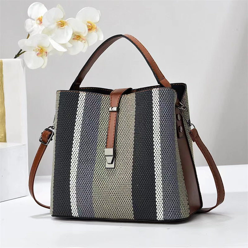 Goran Striped handbag with brown accents on a white surface with flowers in the background