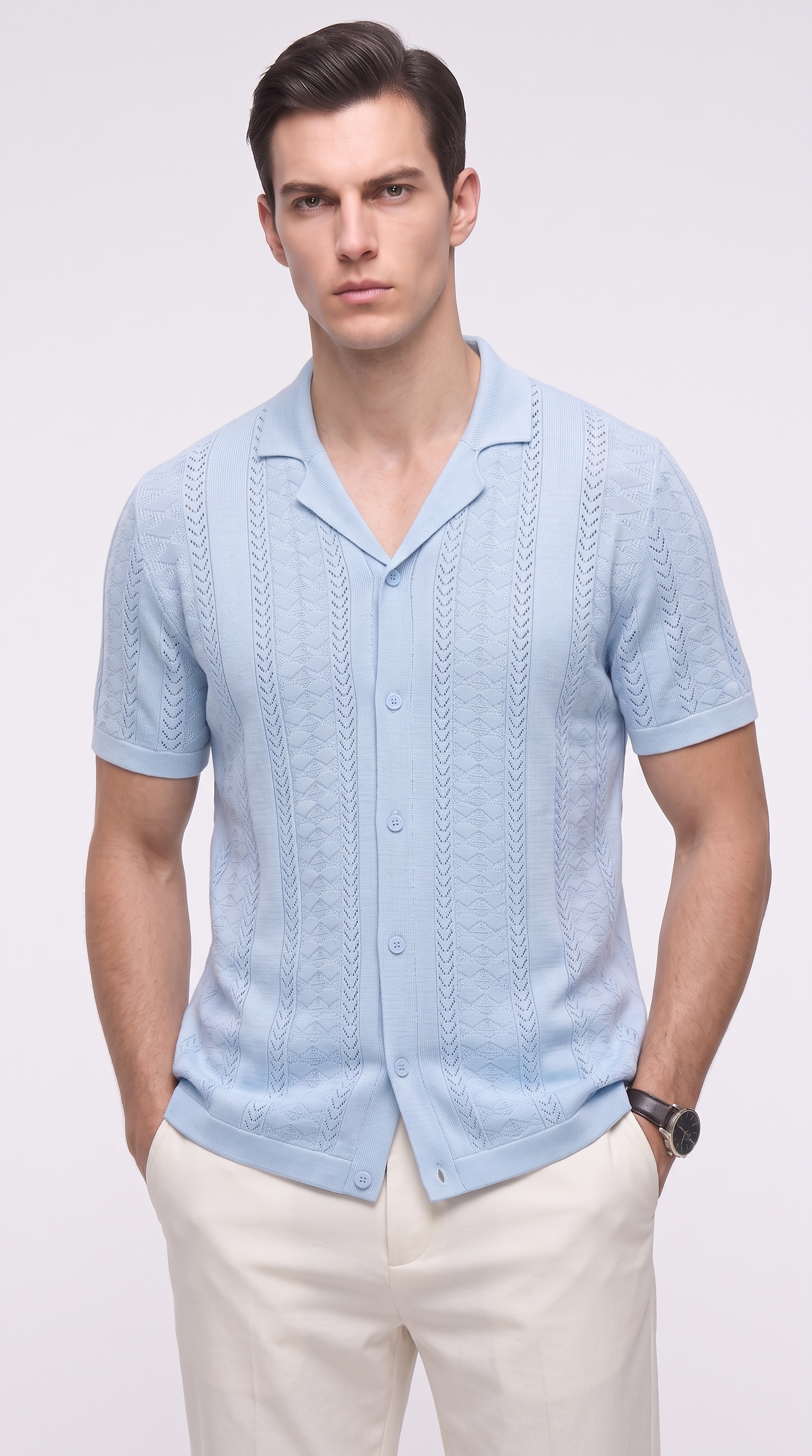 A man wearing a light blue short-sleeve knit button-up shirt with a textured cable pattern, paired with off-white trousers, photographed against a plain light gray studio background, from Meleche Fashion USA or Meléche (short as (Mé))
