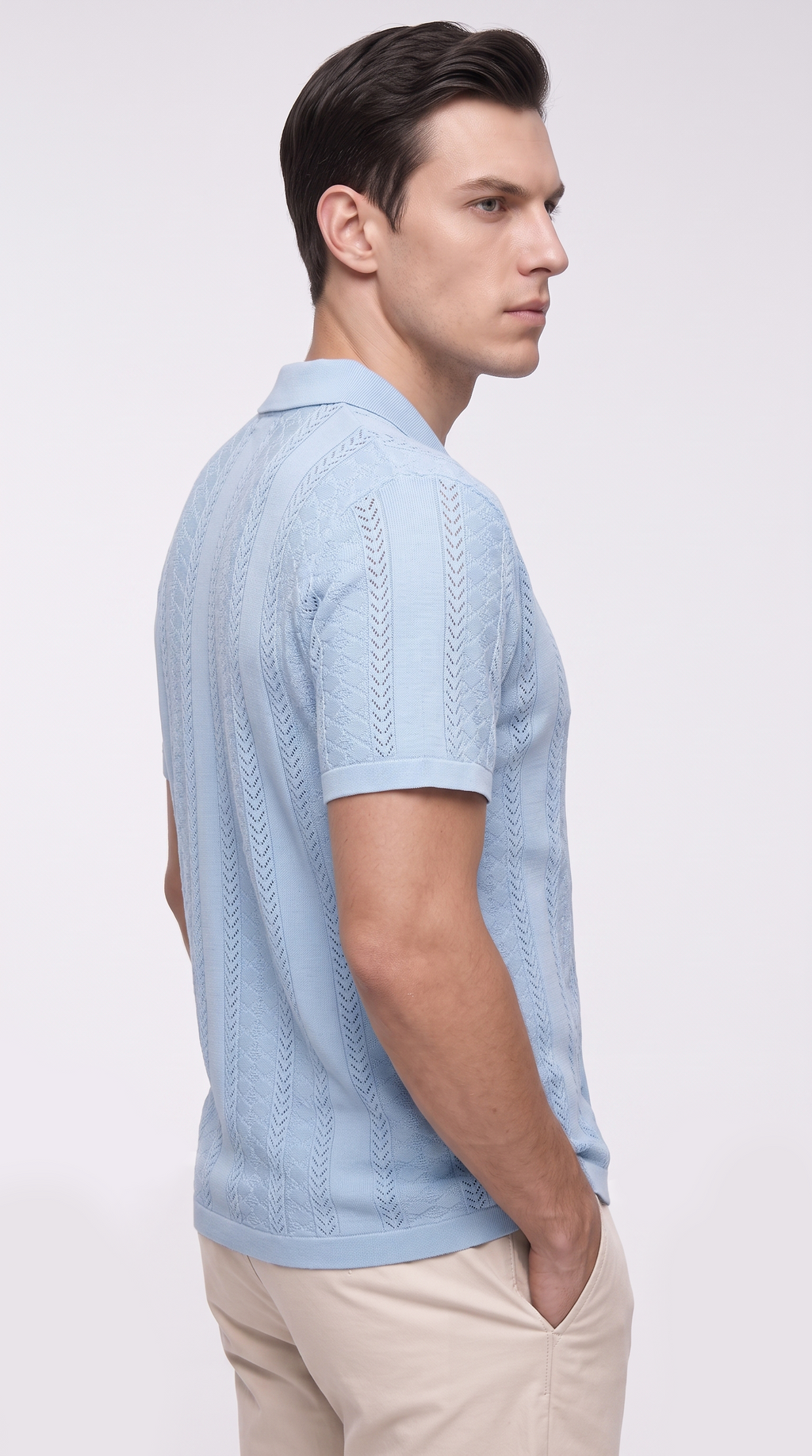 A man in a light blue short-sleeve knit polo shirt with textured vertical cable patterns, paired with beige trousers, shown from a side profile against a light gray studio background, from Meleche Fashion USA or Meléche (short as (Mé))