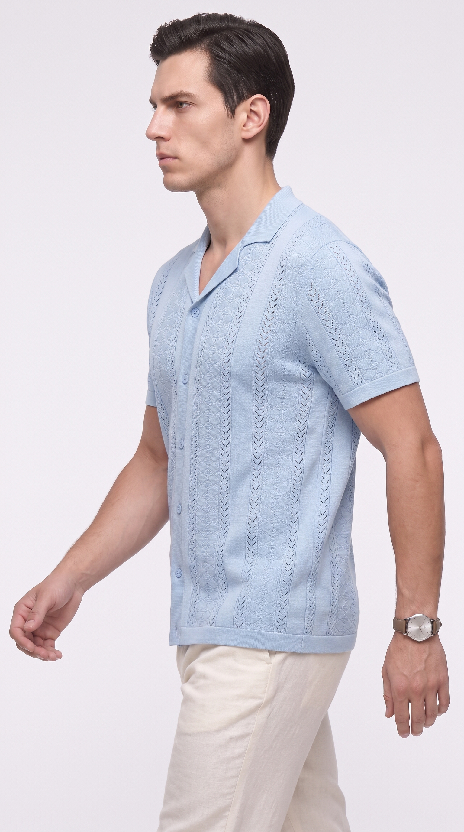 A man wearing a light blue short-sleeve knit button-up shirt with a textured vertical pattern, paired with cream trousers, photographed against a plain light gray studio background, from Meleche Fashion USA or Meléche (short as (Mé))