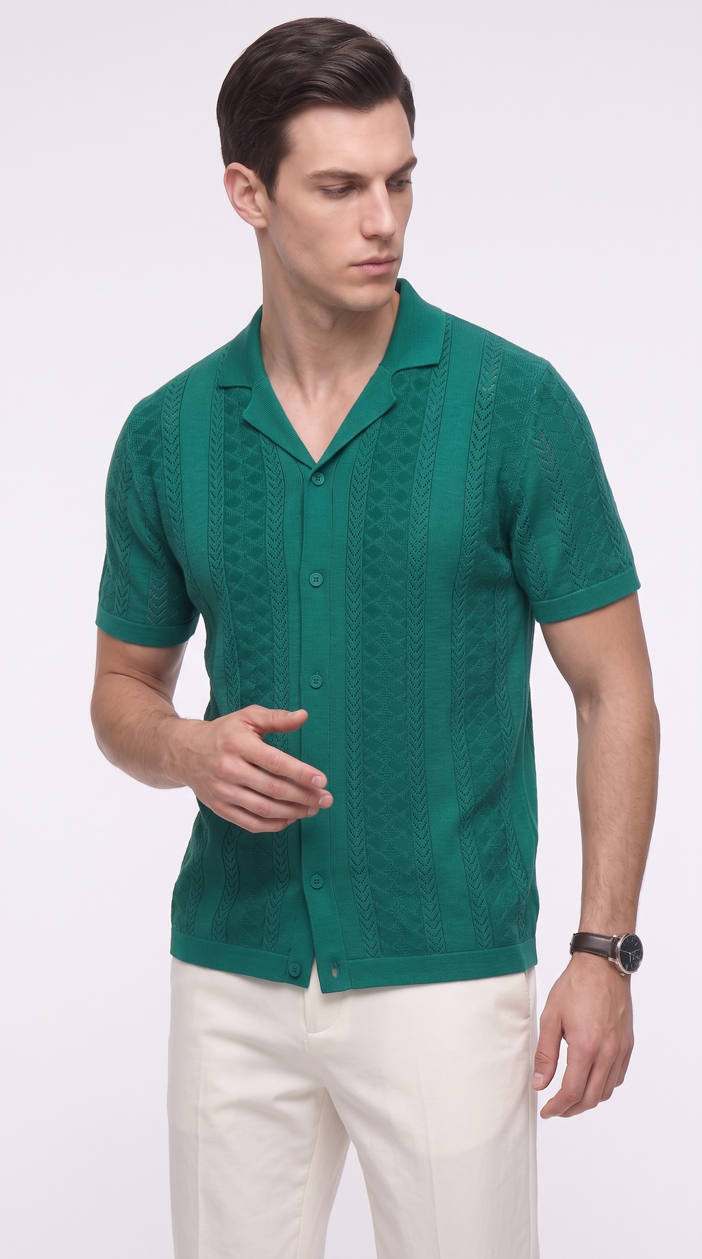 A man wearing a green short-sleeve knit button-up shirt with a textured chevron pattern, paired with off-white trousers, photographed against a light gray studio background, from Meleche Fashion USA or Meléche (short as (Mé))