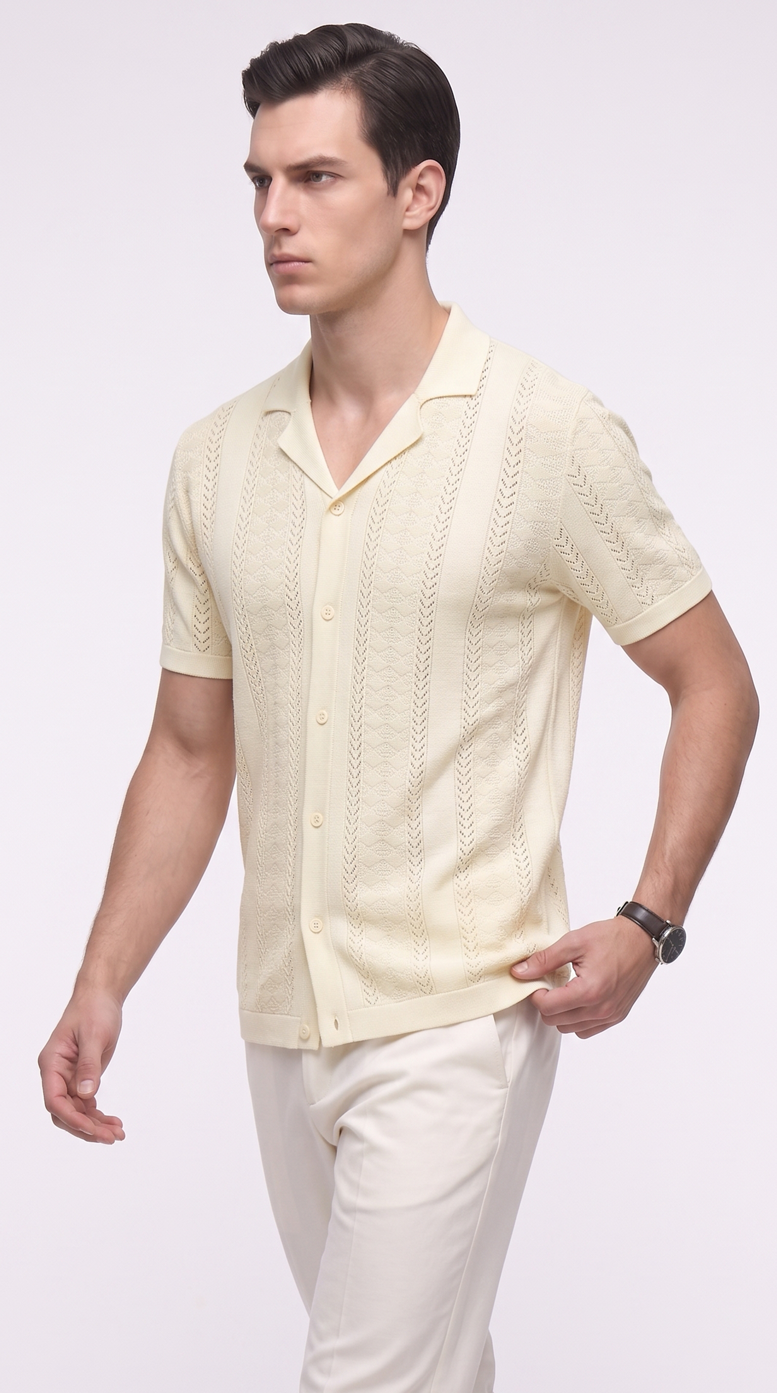 A man wearing a pale cream short-sleeve knit button-up shirt with a textured cable pattern, paired with cream trousers, photographed against a light gray studio background, from Meleche Fashion USA or Meléche (short as (Mé))