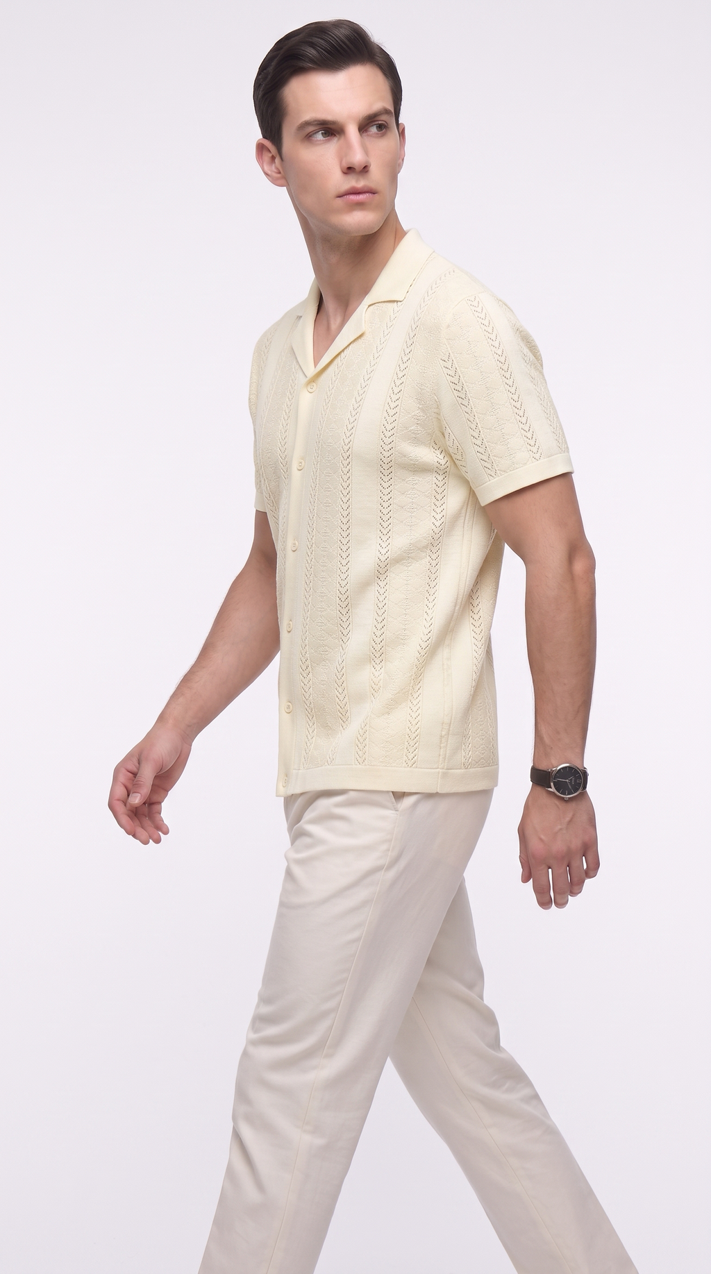 A man wearing a pale cream short-sleeve knit polo shirt and matching cream trousers, walking against a plain light gray studio background, from Meleche Fashion USA or Meléche (short as (Mé))