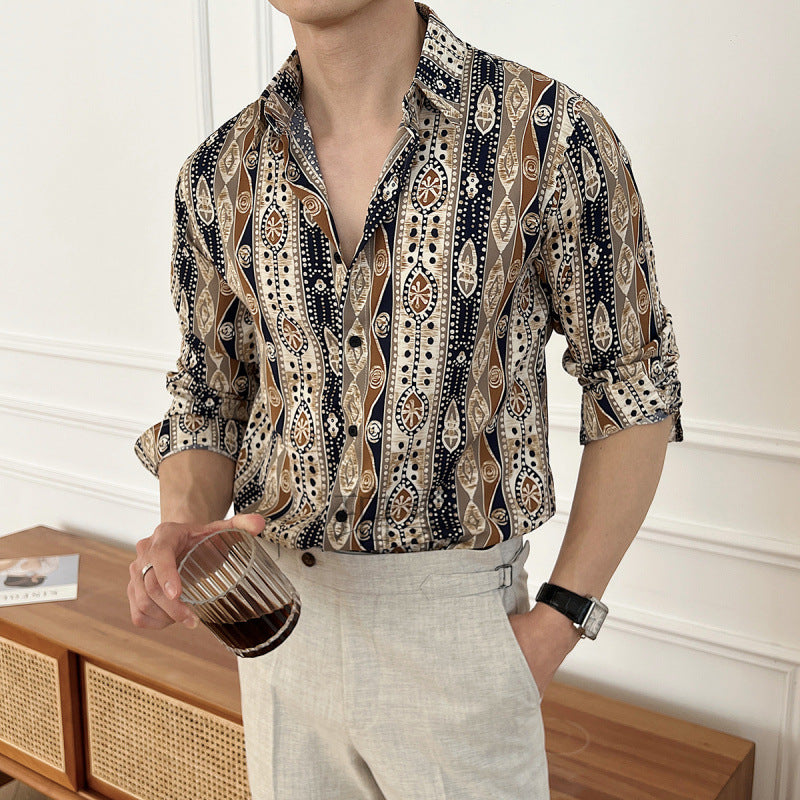 Person wearing a patterned shirt and light pants, holding a glass with a dark liquid.