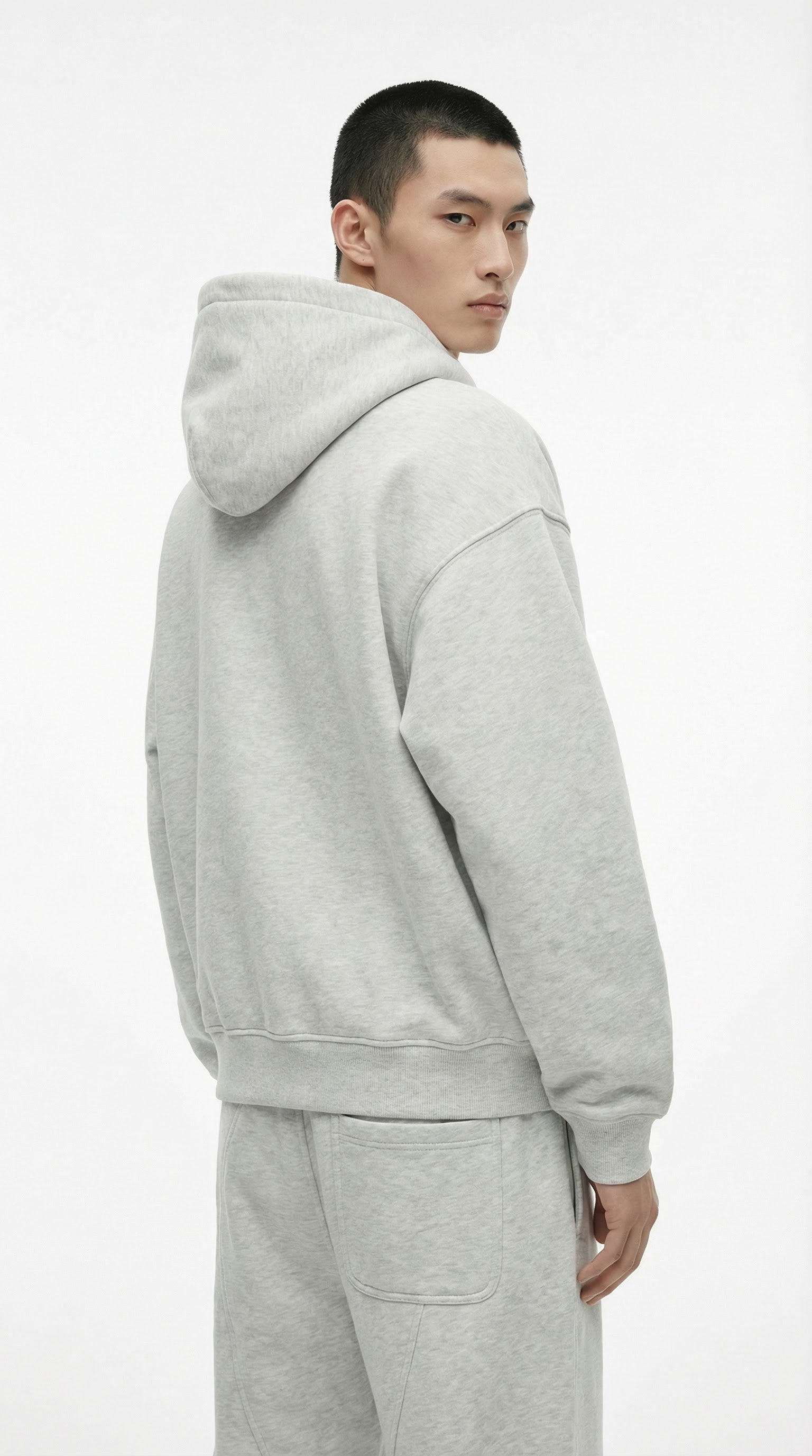 Person wearing a gray fleece-lined tracksuit with text indicating thickness, standing against a plain background.