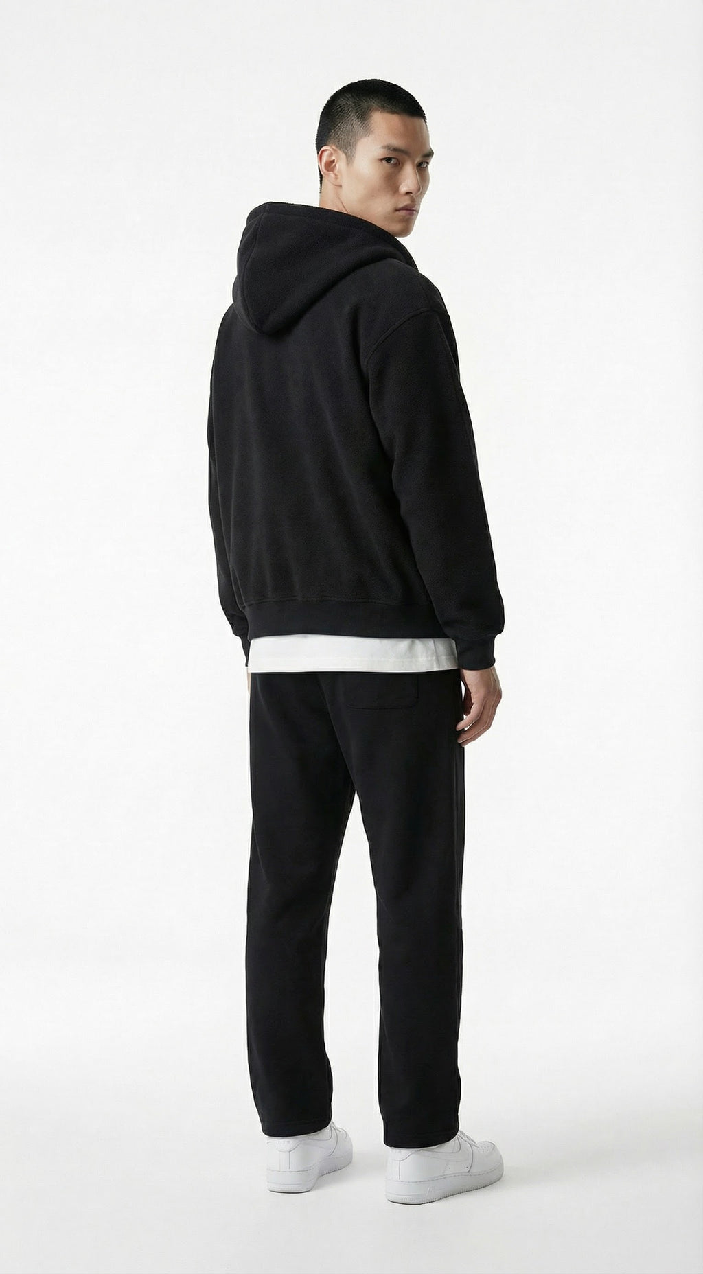 Person wearing a gray tracksuit against a concrete wall.