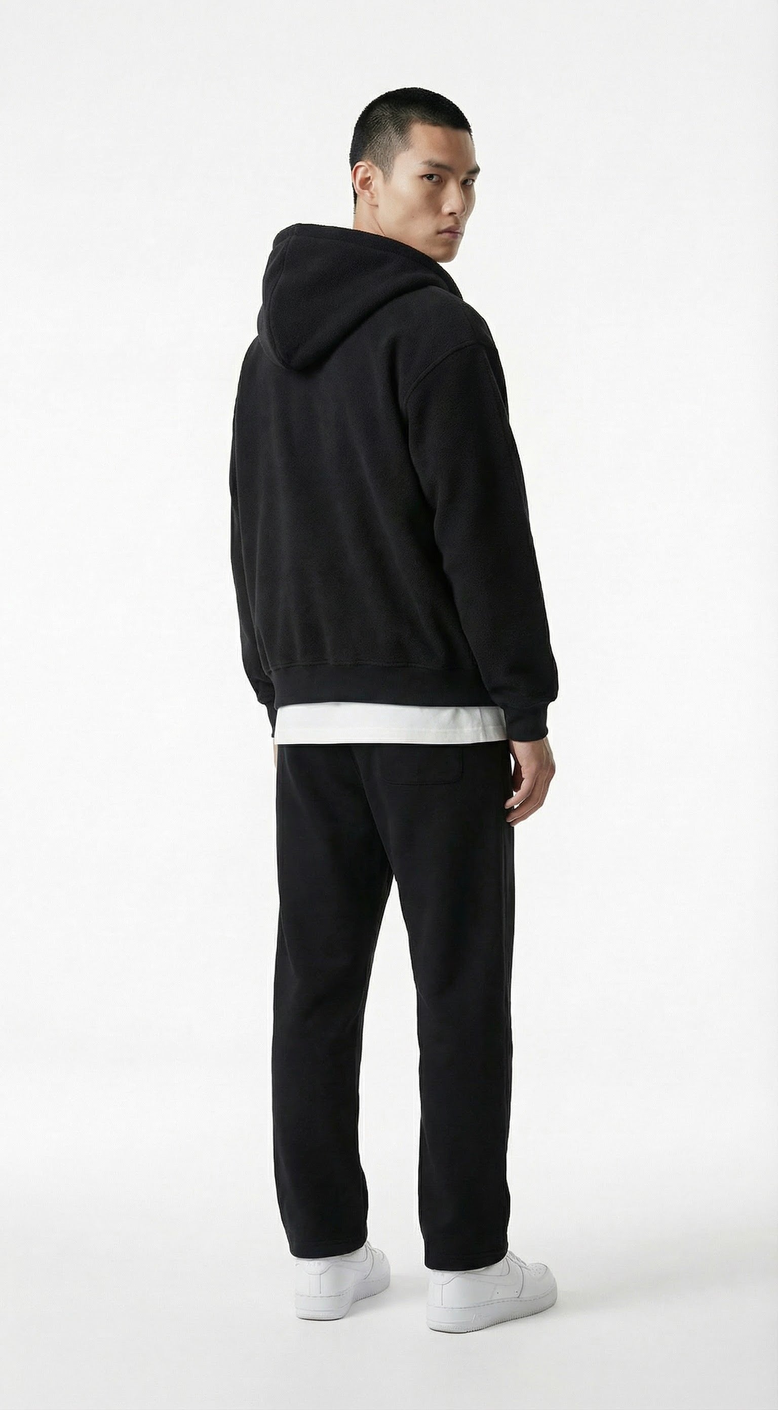 Person wearing a gray tracksuit against a concrete wall.