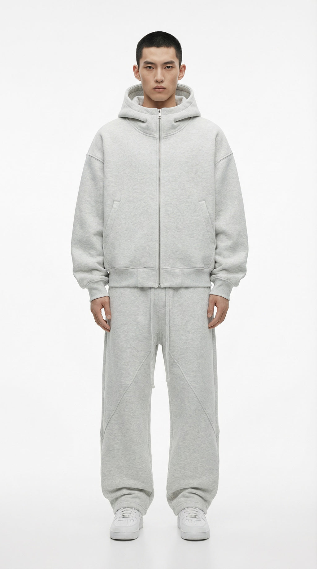 Person wearing a gray fleece-lined tracksuit with text indicating thickness, standing against a plain background.