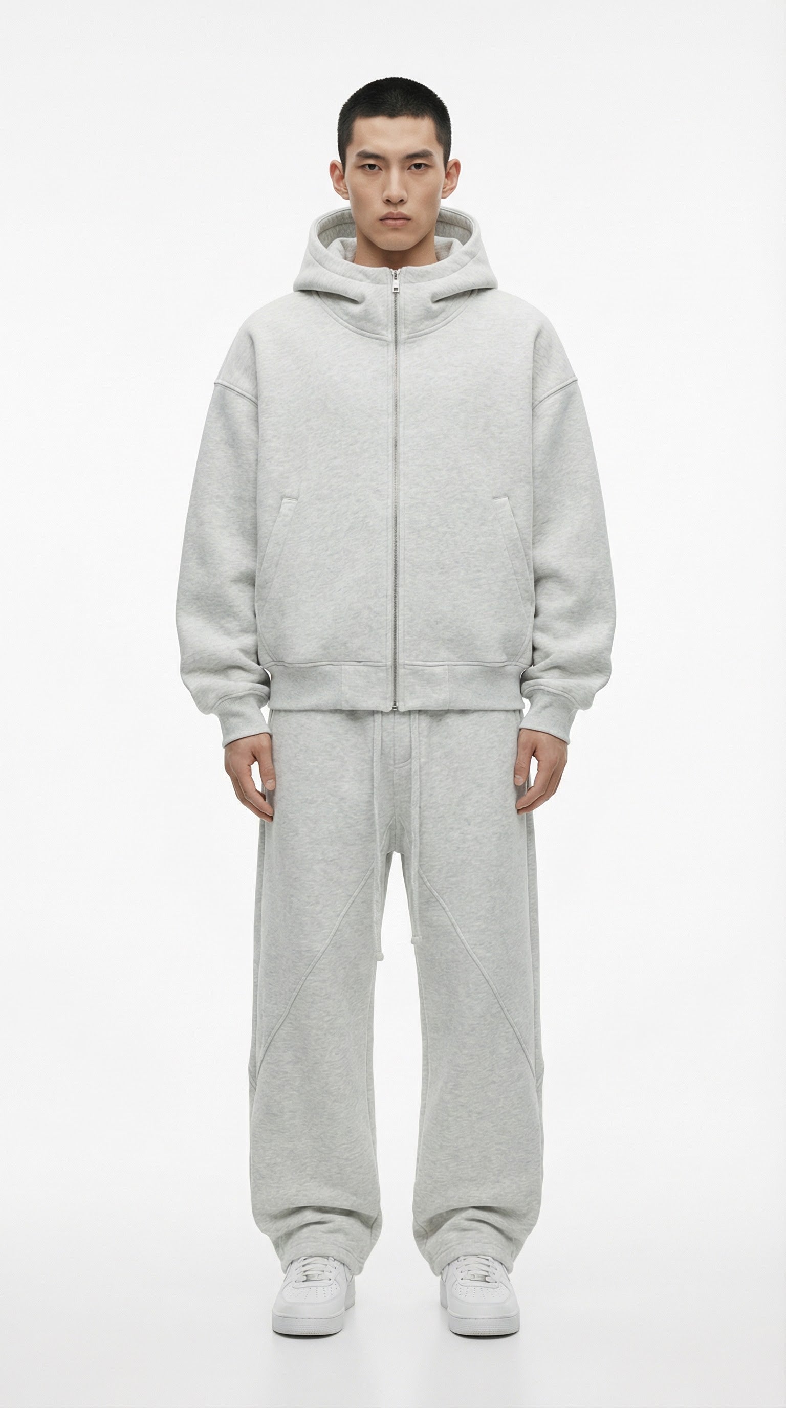 Person wearing a gray fleece-lined tracksuit with text indicating thickness, standing against a plain background.