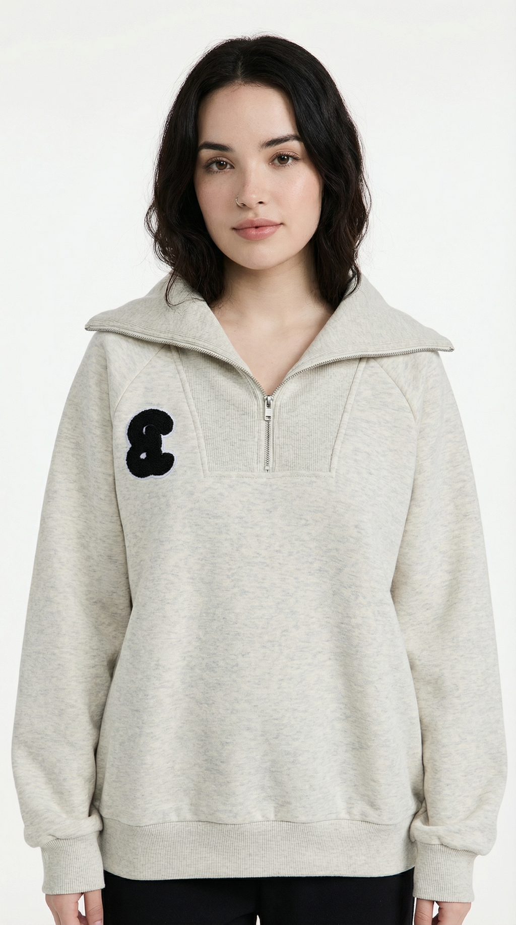 Woman wearing a light gray pullover with a black logo on a white background
