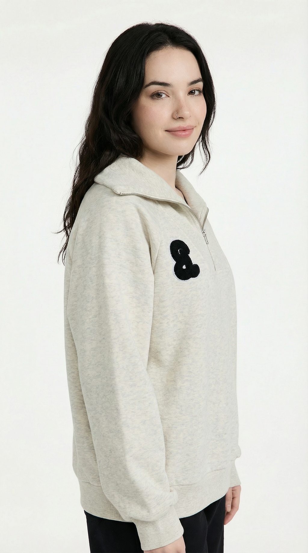 Woman wearing a light-colored hoodie with a black flower accessory on a white background
