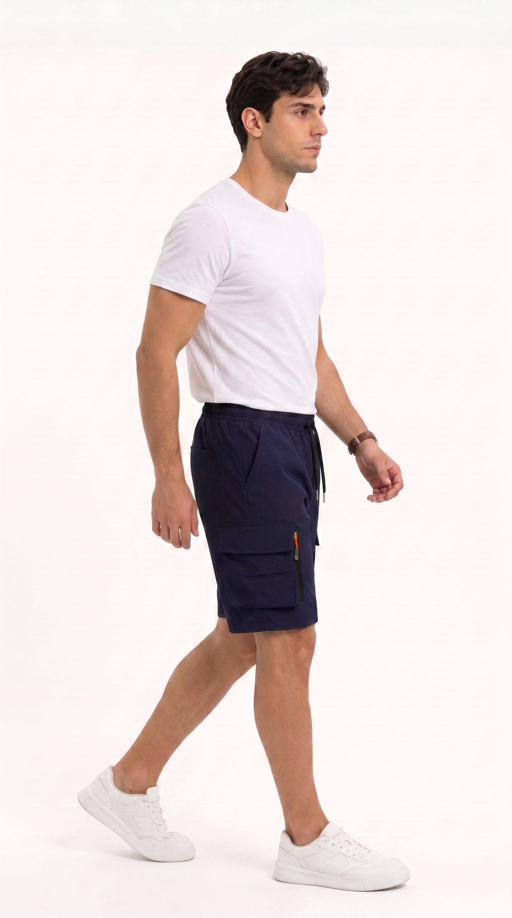 A man in a white t-shirt and navy blue cargo shorts walking in profile against a plain white studio background, from Meleche Fashion USA or Meléche (short as (Mé))