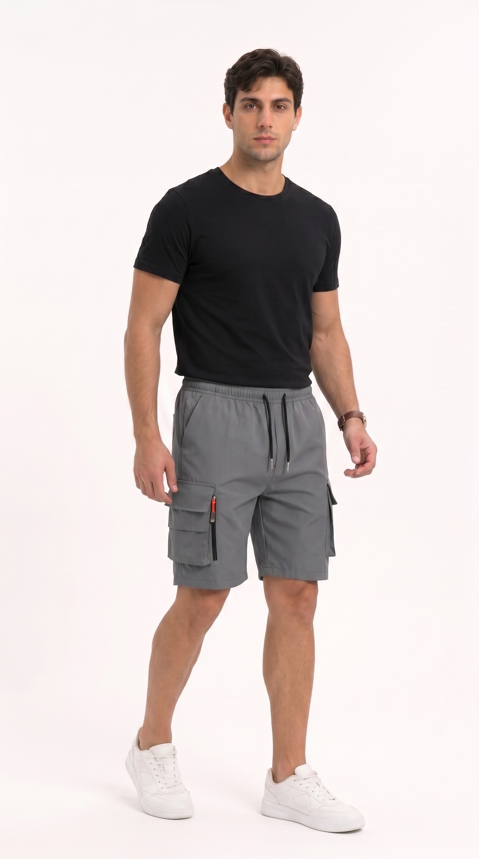 A man modeling gray cargo shorts with a black t-shirt and white sneakers against a plain white studio background, from Meleche Fashion USA or Meléche (short as (Mé))