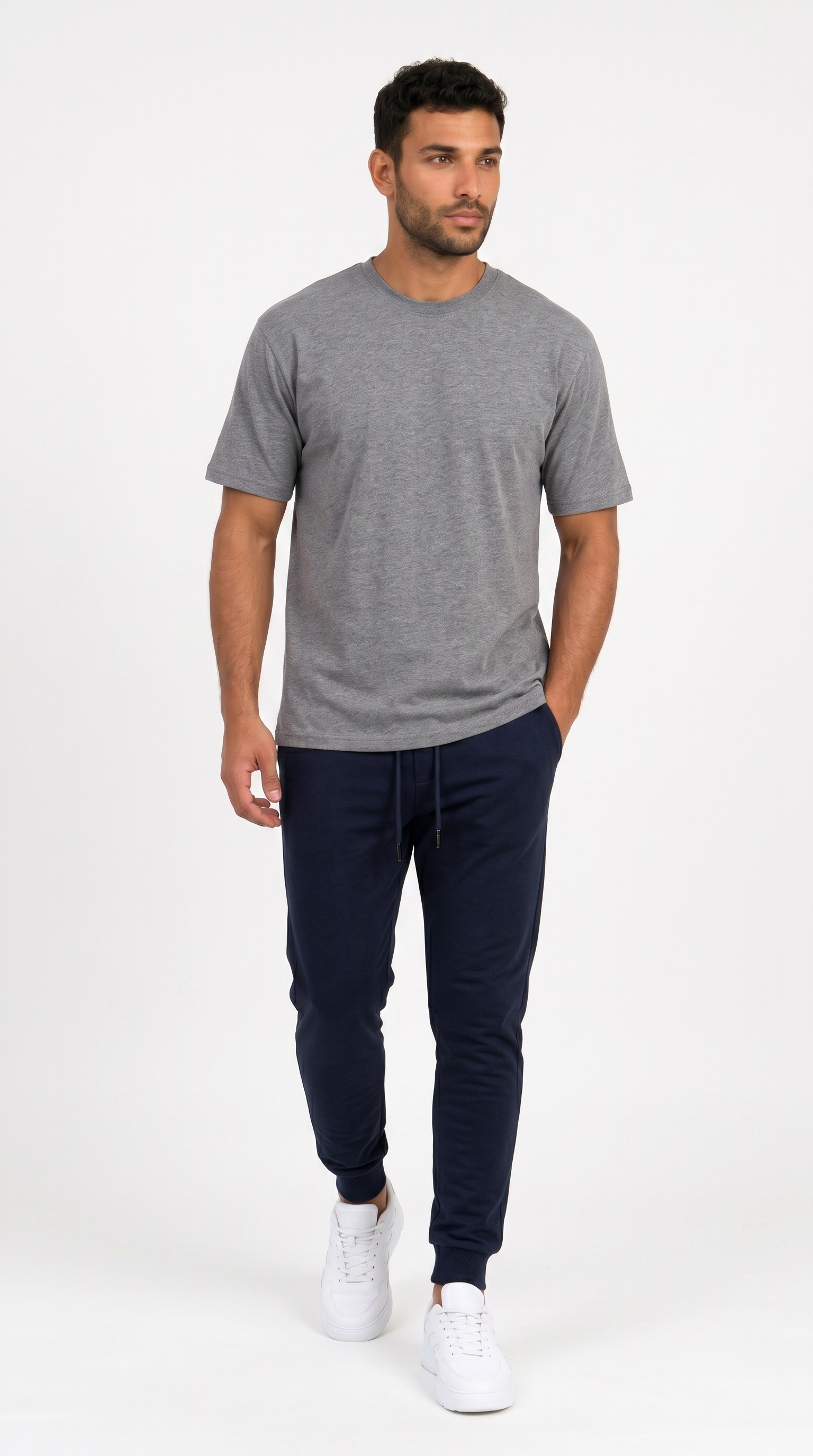 A man modeling a heather gray short-sleeve crewneck t-shirt, dark navy jogger pants, and white sneakers against a plain white studio background, from Meleche Fashion USA or Meléche (short as (Mé))