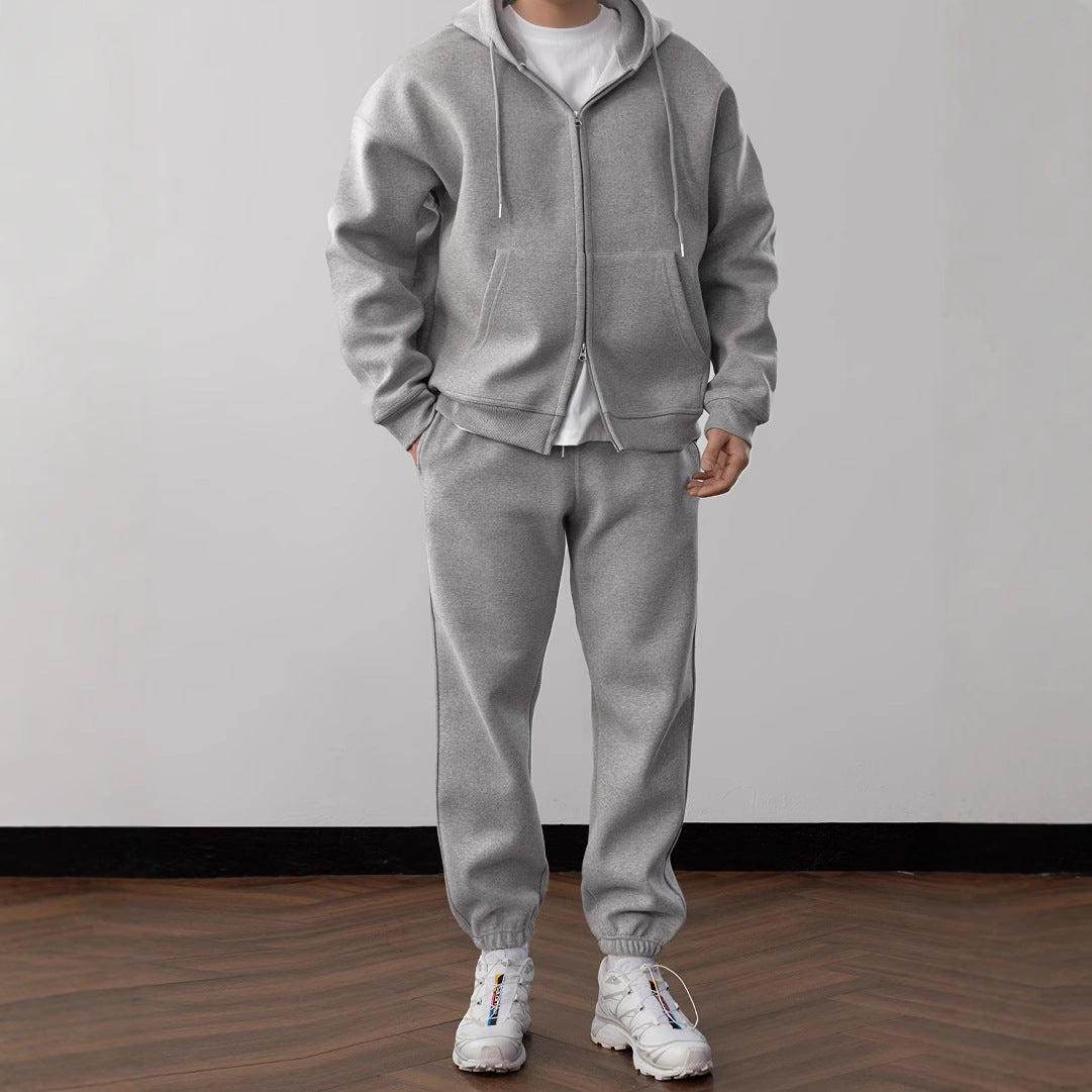 Person wearing a gray tracksuit with white sneakers on a plain background