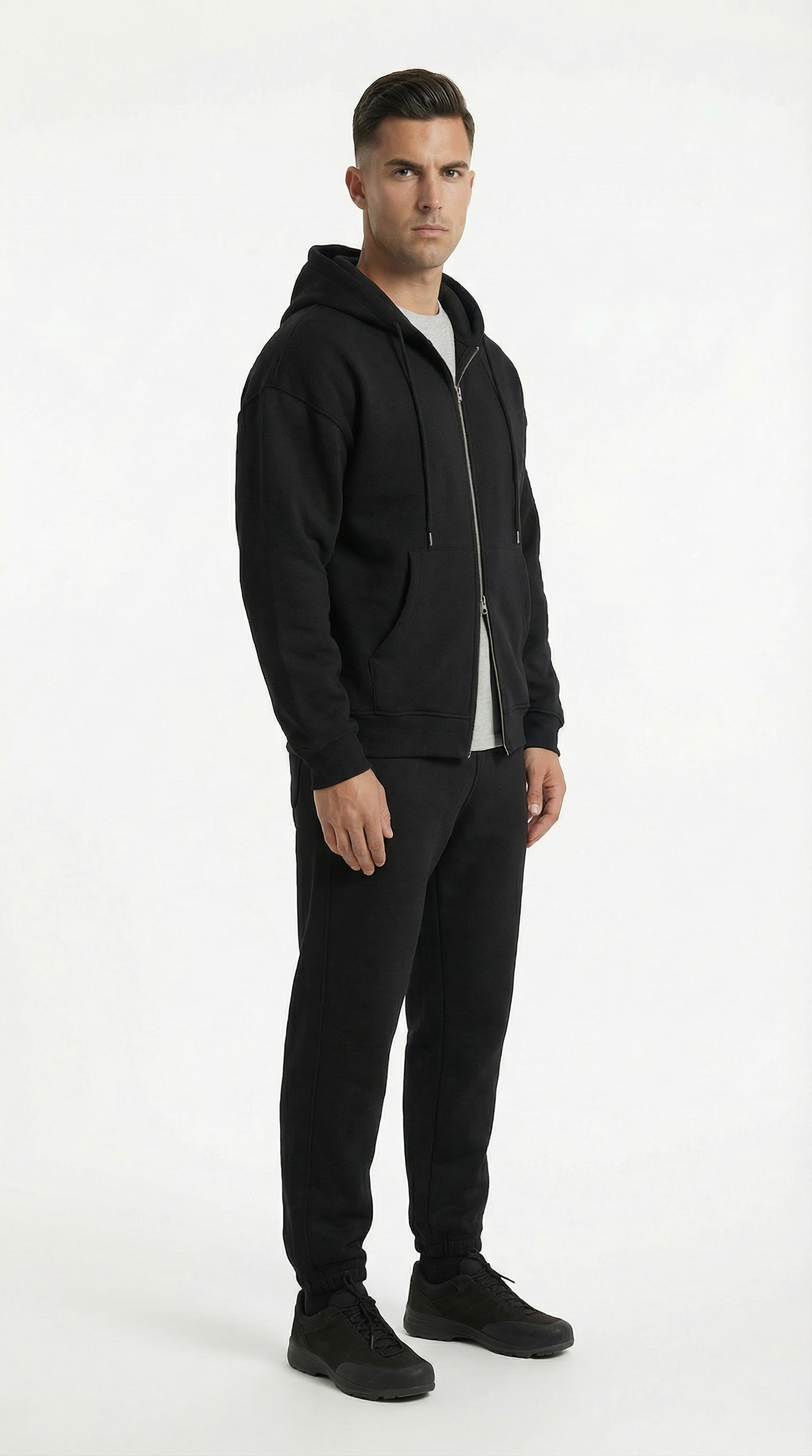 Man wearing a black hoodie and pants on a white background