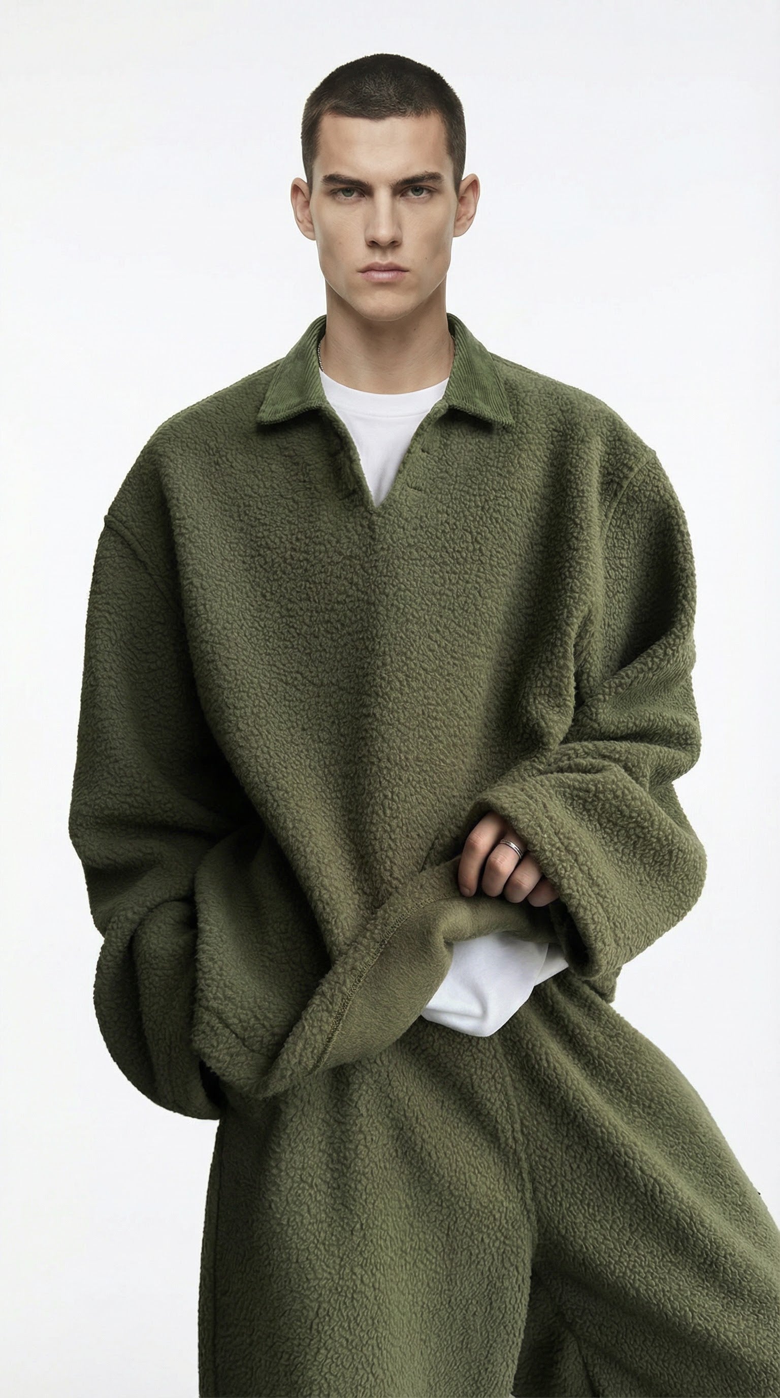 Man wearing a green oversized sweater over a white shirt on a white background
