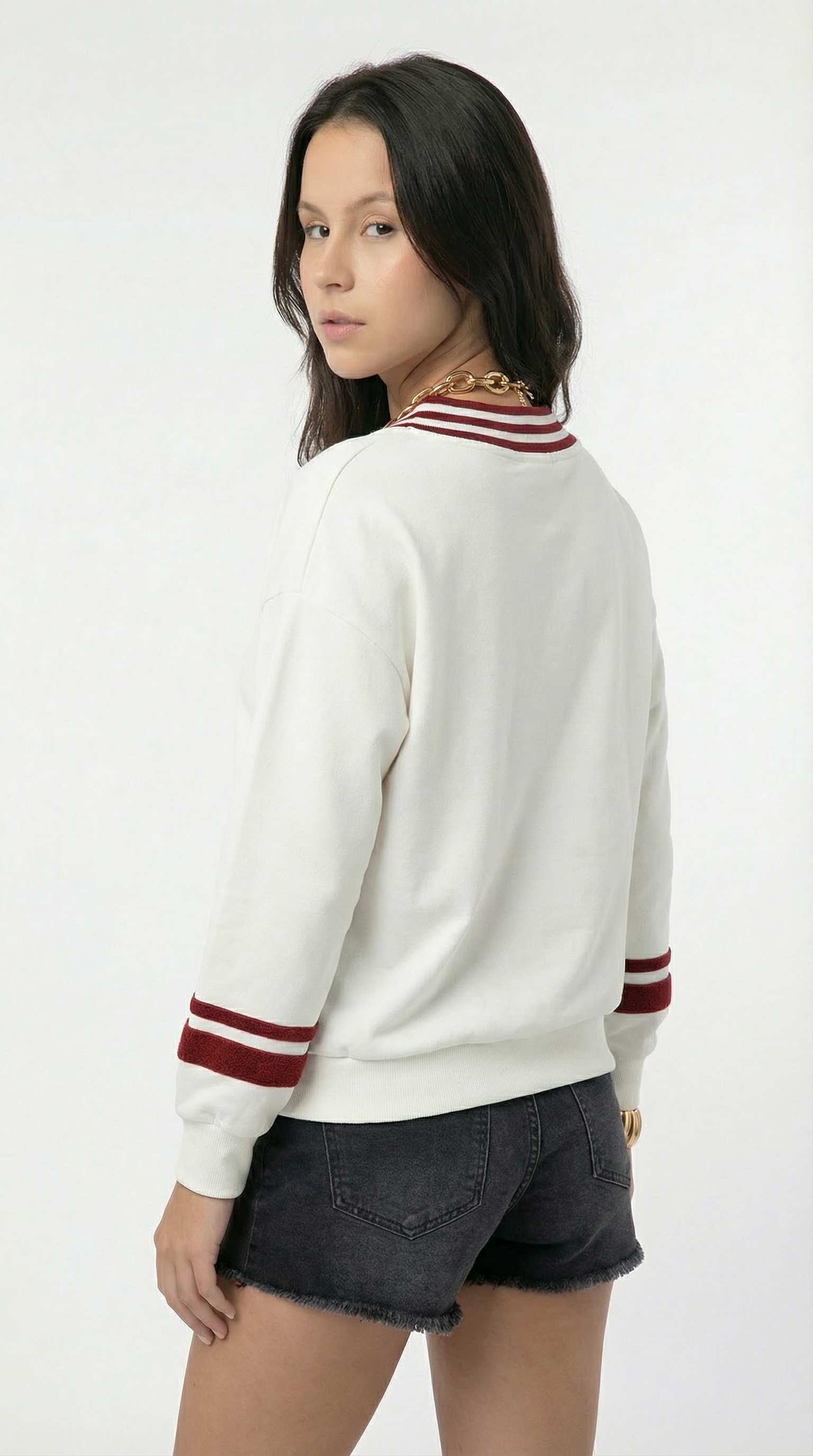 Person wearing a white sweater with red accents on a white background