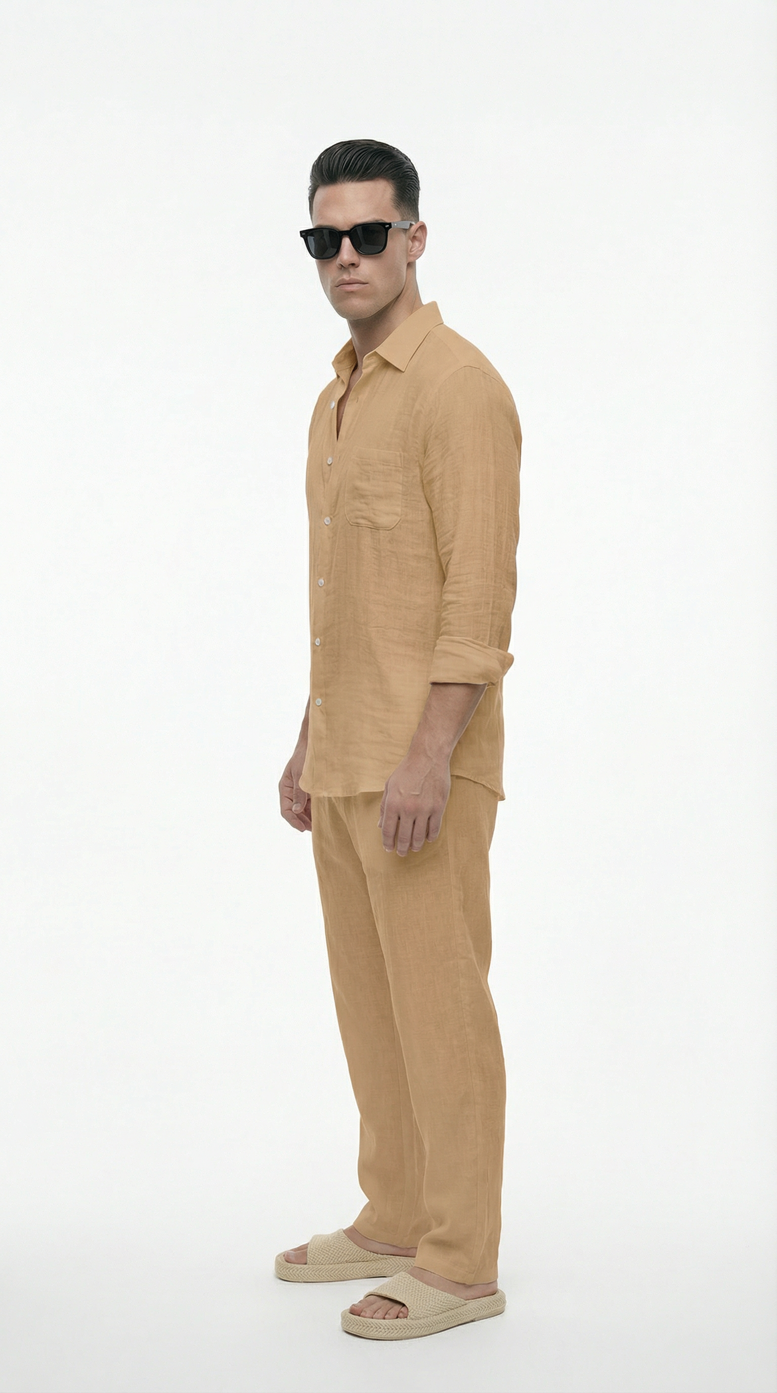 Man wearing a beige shirt and pants with sunglasses on a white background