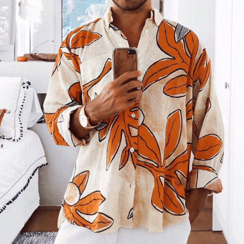 Person wearing a patterned shirt with orange leaves indoors.