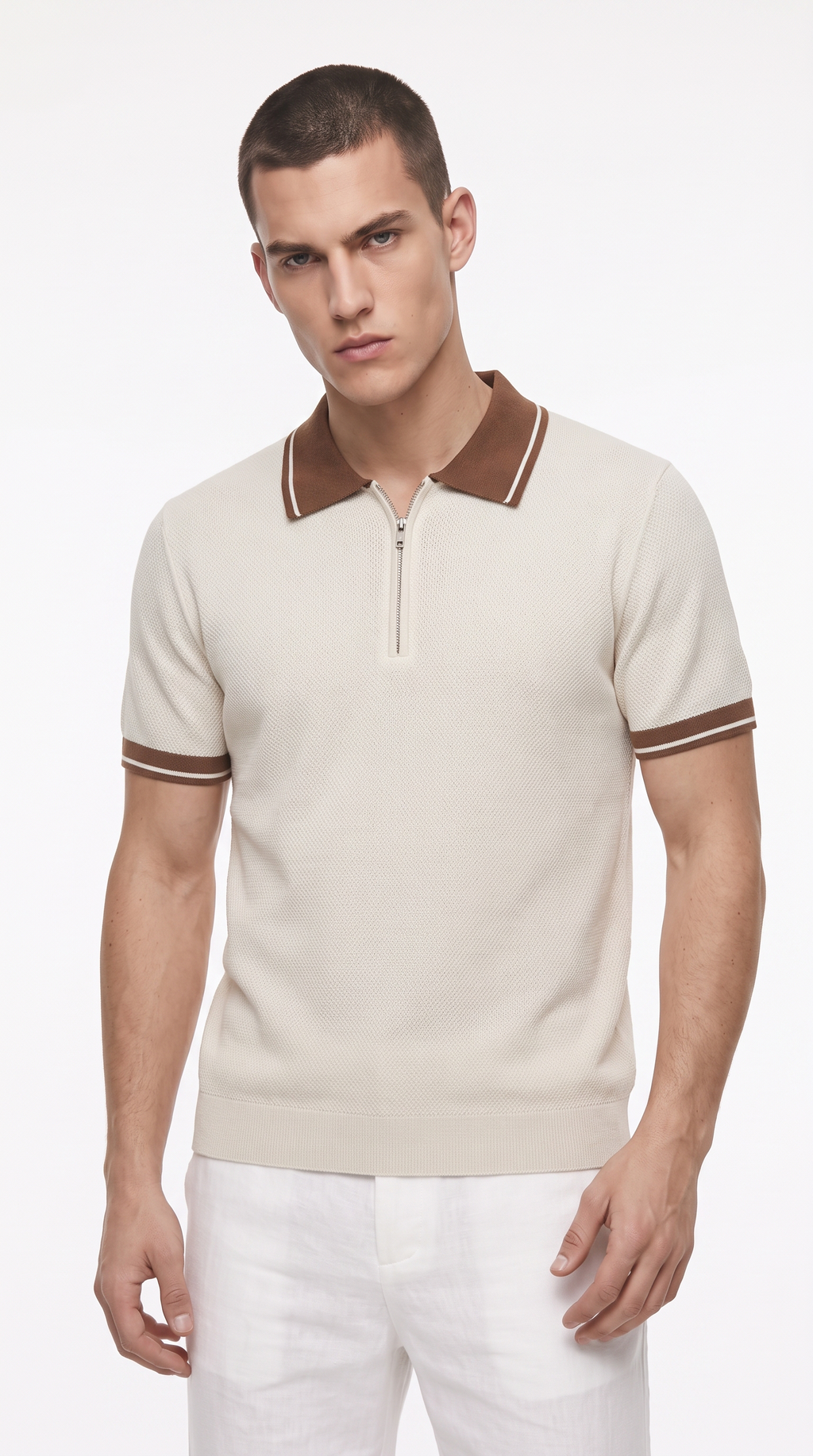 A male model wearing a short-sleeve knit polo shirt in cream with brown collar and sleeve trim, paired with white trousers, against a plain white studio background, from Meleche Fashion USA or Meléche (short as (Mé))