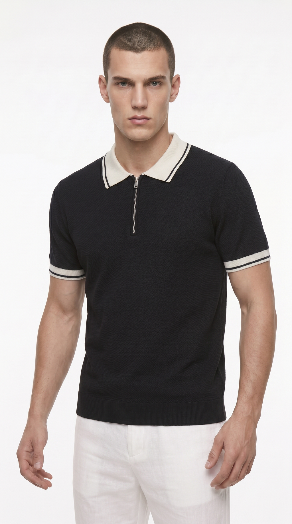 A man modeling a black short-sleeve knit polo shirt with a half-zip collar and white striped accents on the collar and sleeve cuffs, paired with white trousers, against a plain white studio background, from Meleche Fashion USA or Meléche (short as (Mé))