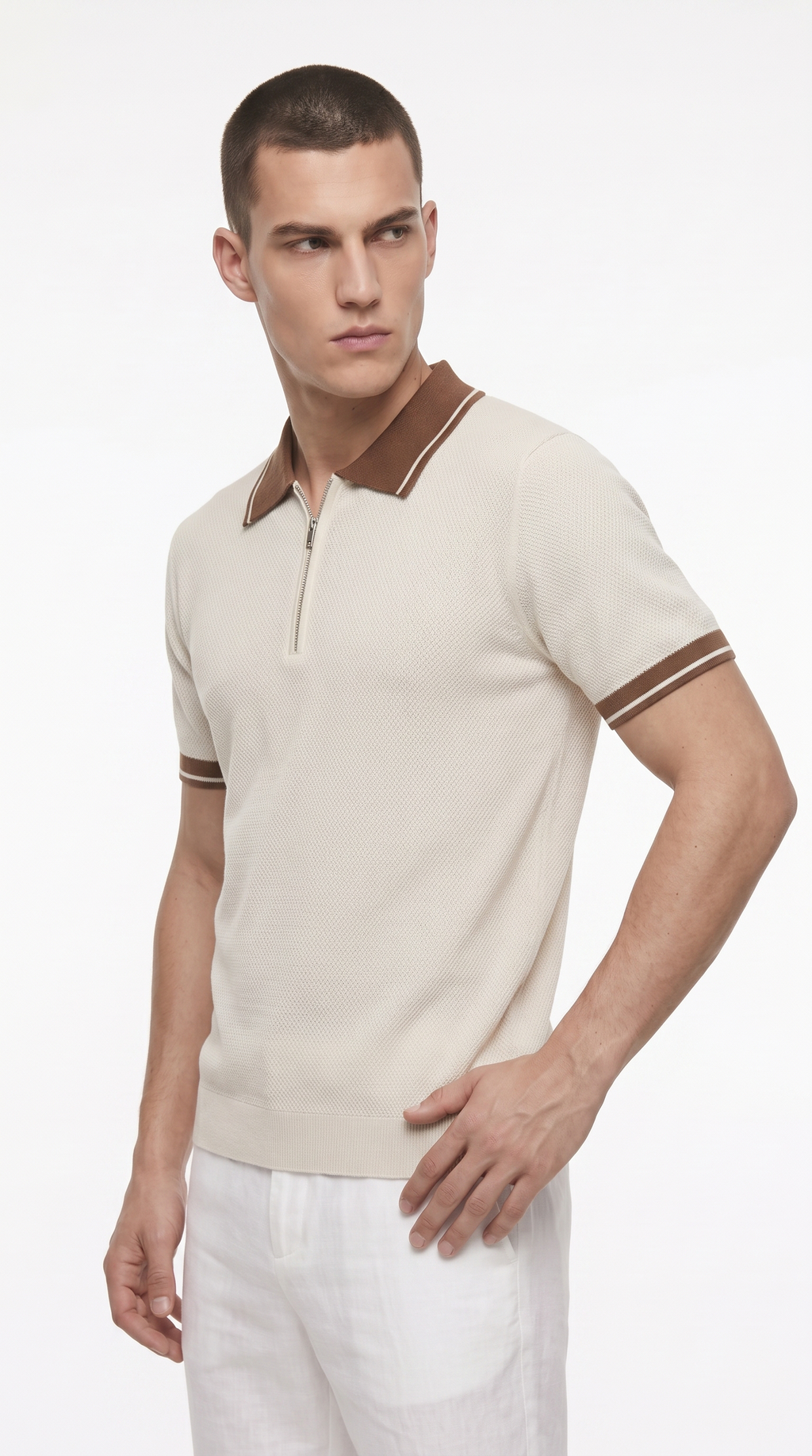 A man modeling a short-sleeve knit polo shirt in off-white with brown trim on the collar and sleeve cuffs, paired with white trousers, against a plain white studio background, from Meleche Fashion USA or Meléche (short as (Mé))