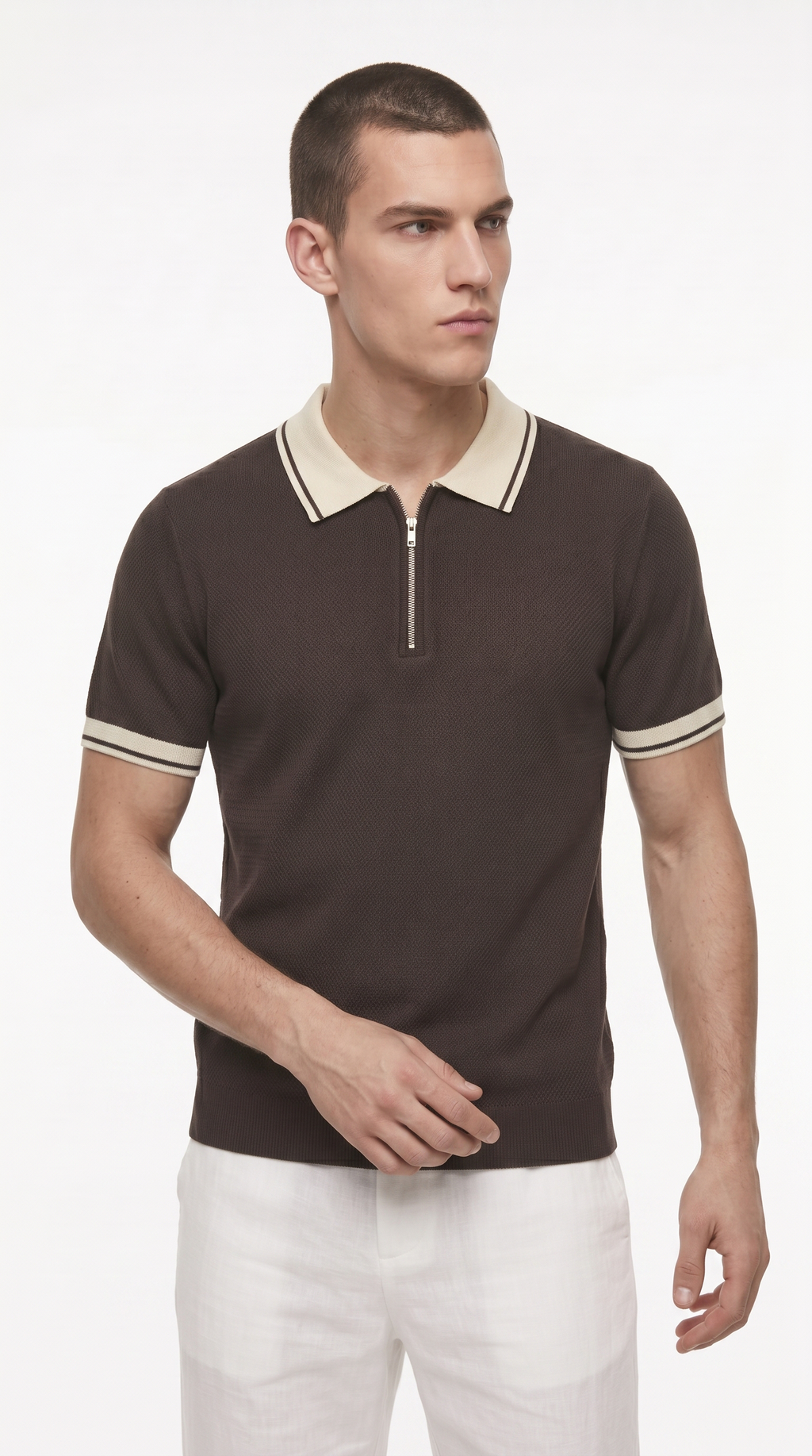 A man wearing a dark brown short-sleeve polo shirt with a cream collar and sleeve trim, paired with white trousers, photographed against a plain light background, from Meleche Fashion USA or Meléche (short as (Mé))
