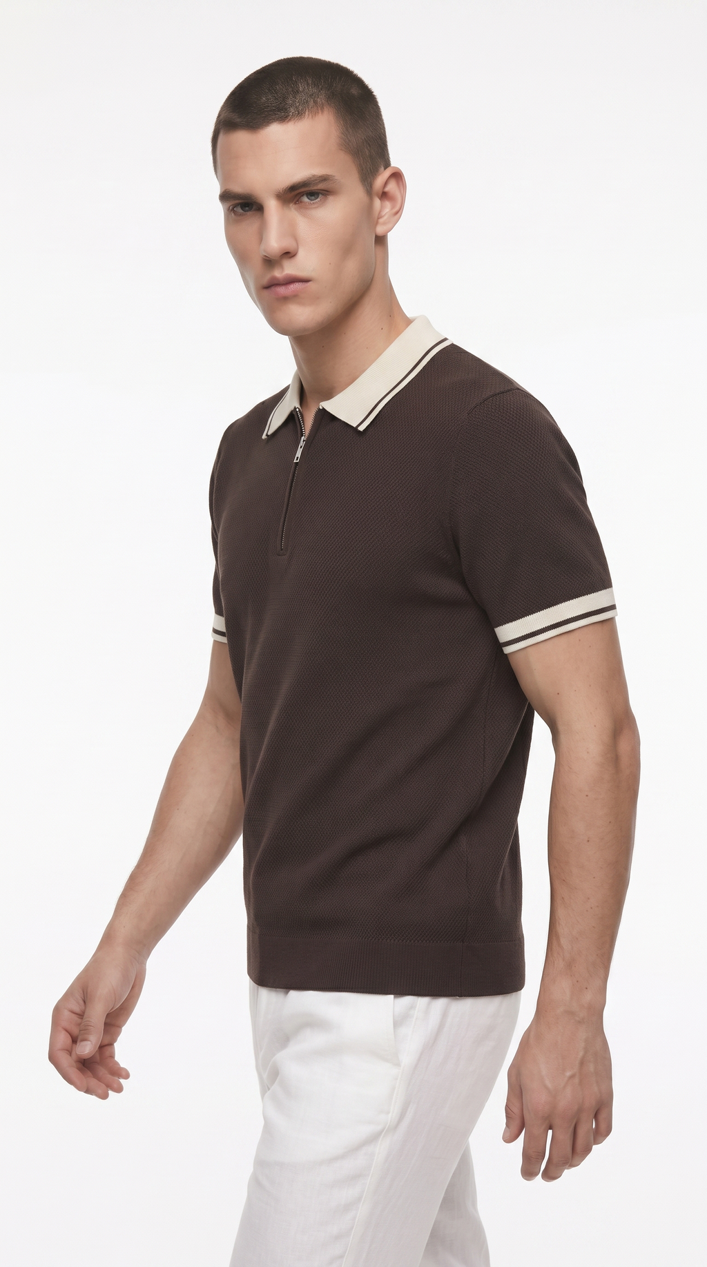 A man wearing a dark brown short-sleeve polo shirt with a cream collar and sleeve stripes, paired with white trousers, photographed against a plain white studio background, from Meleche Fashion USA or Meléche (short as (Mé))