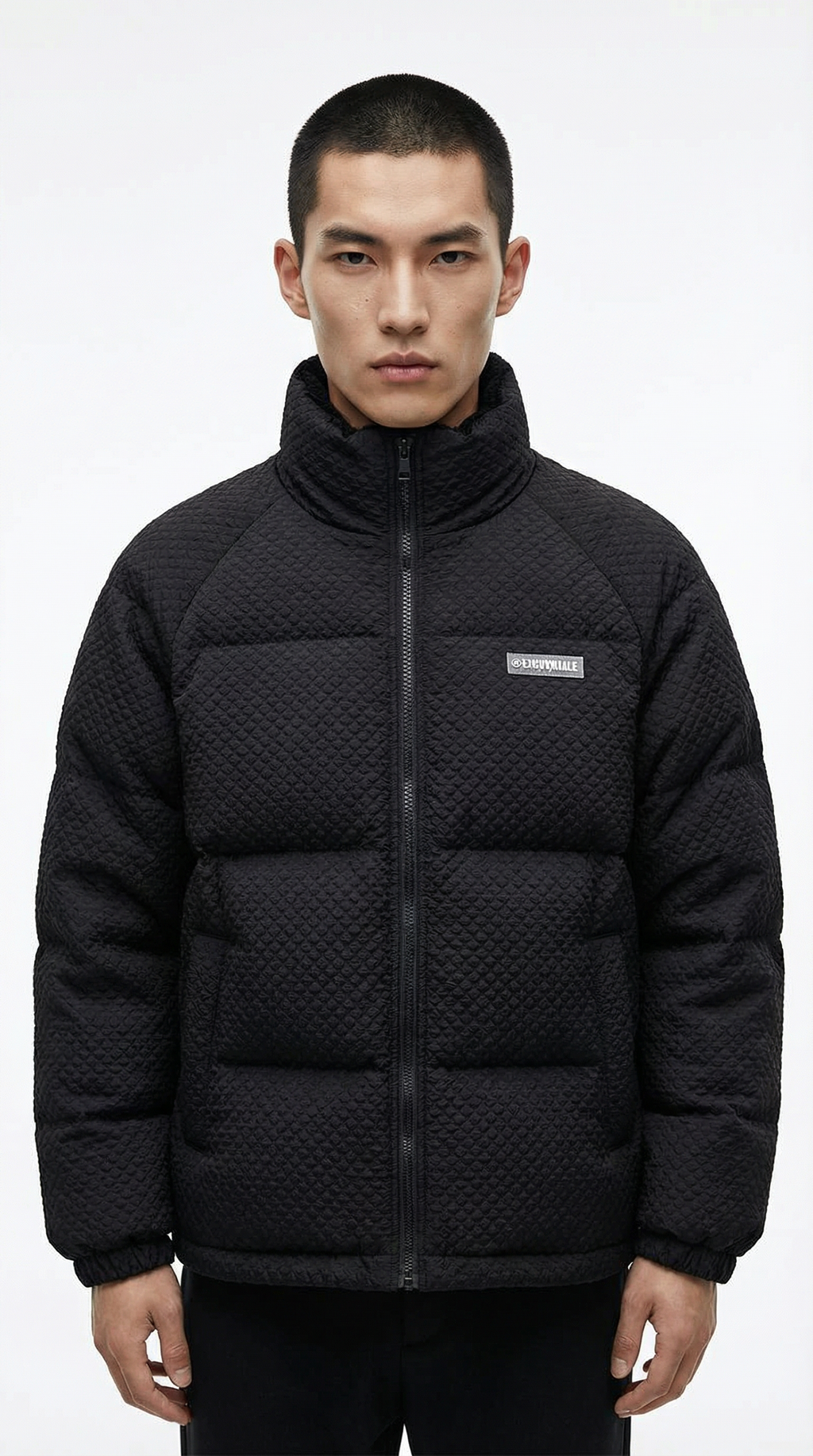 Man wearing a black quilted jacket with a brand logo on a white  from Meleche or Meléche (short as (Mé))background