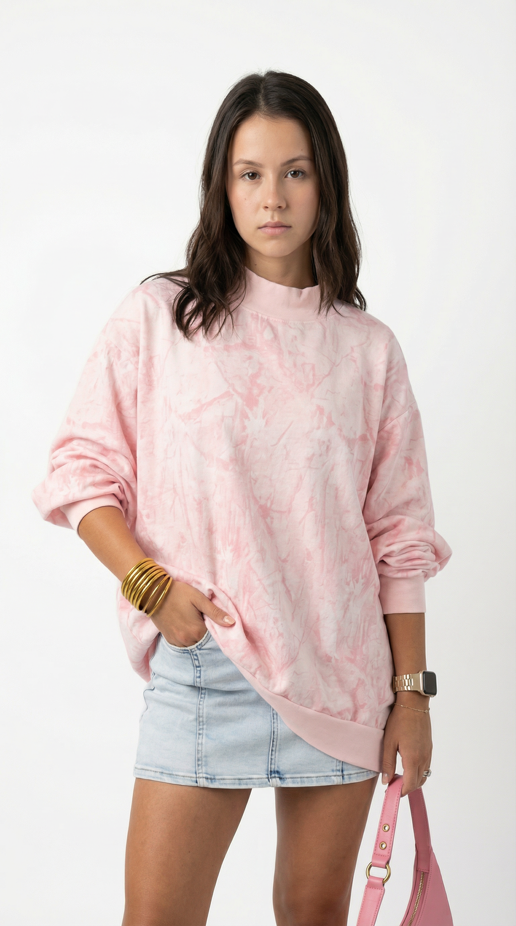 Woman wearing a pink tie-dye sweatshirt and denim shorts on a white background