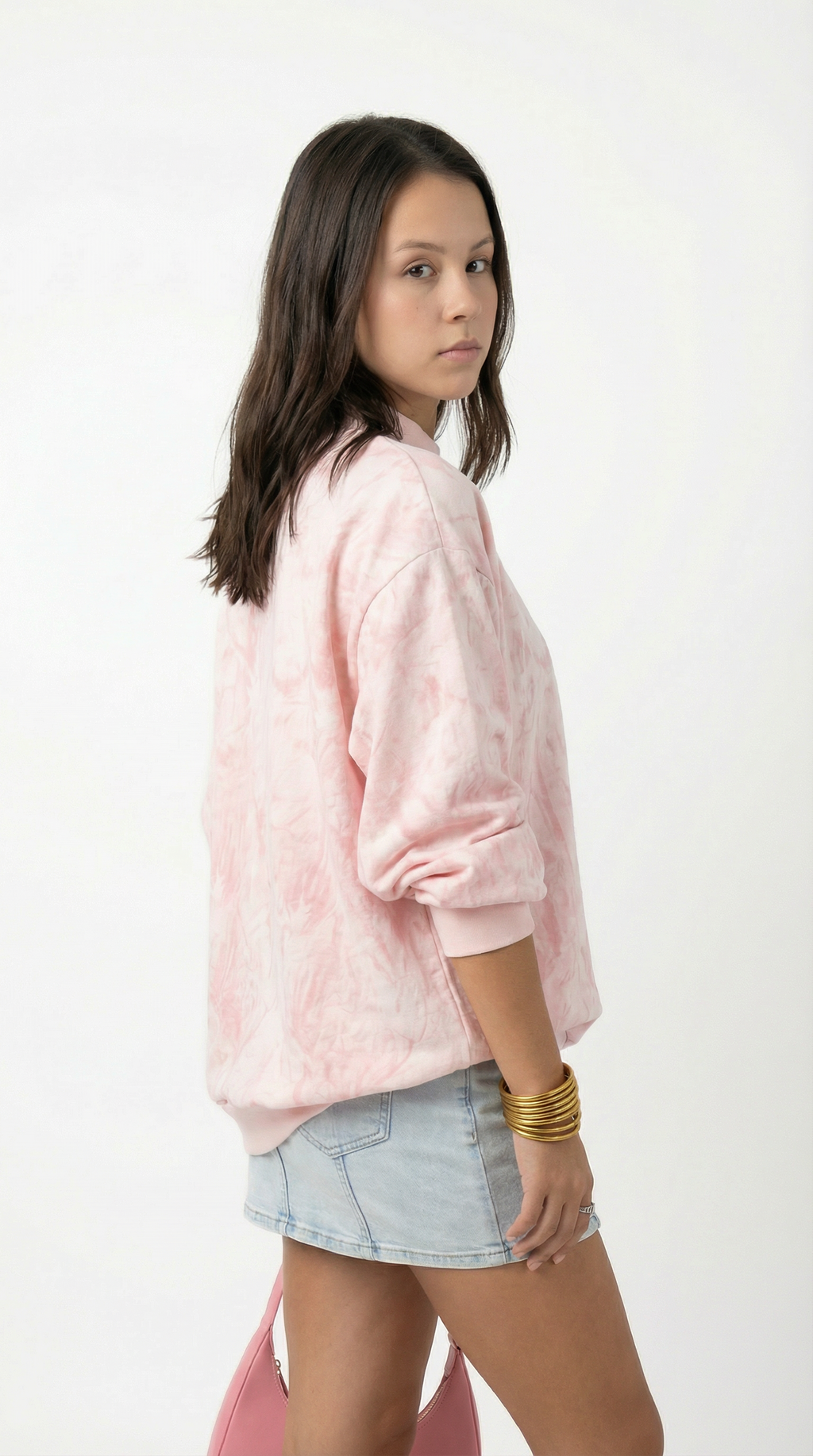 Person wearing a pink jacket and light blue denim shorts on a white background