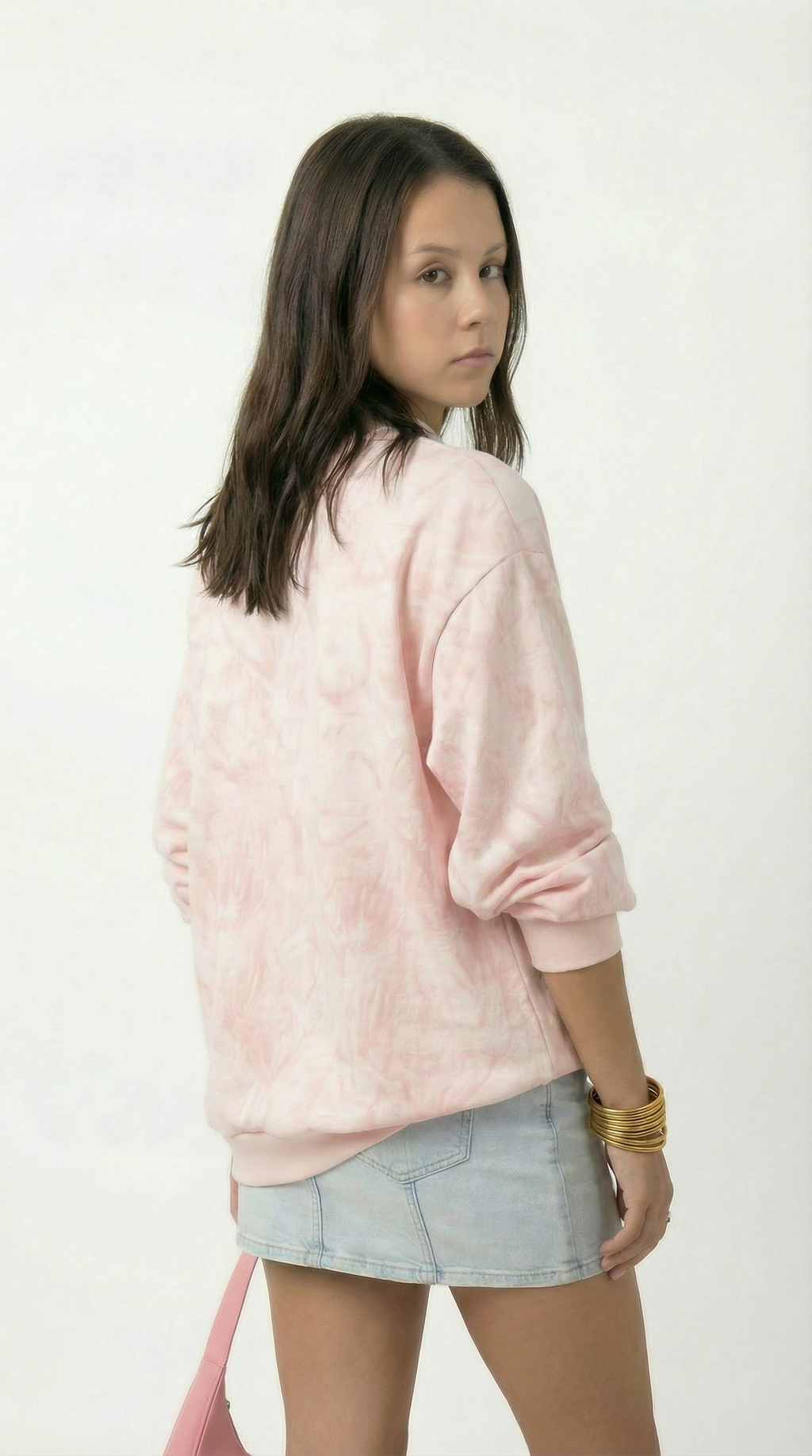 Person wearing a pink sweater and light blue shorts on a white background