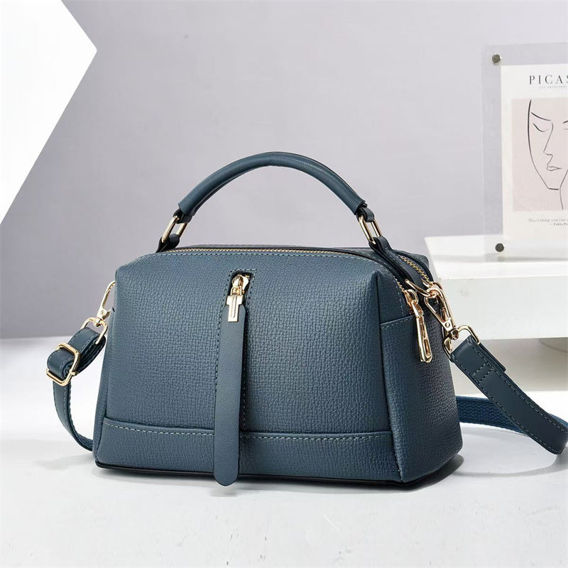 Oleg bag - Blue handbag with gold accents on a white surface